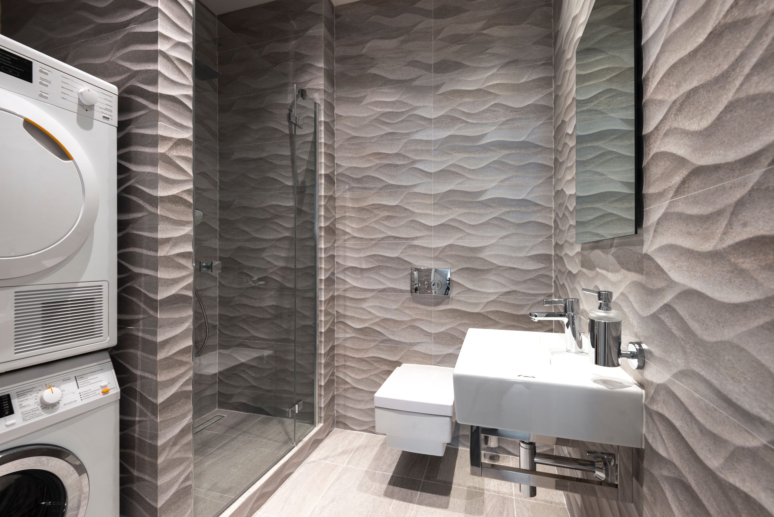 A stylish and contemporary bathroom featuring a shower, sink, and in-built washer and dryer.