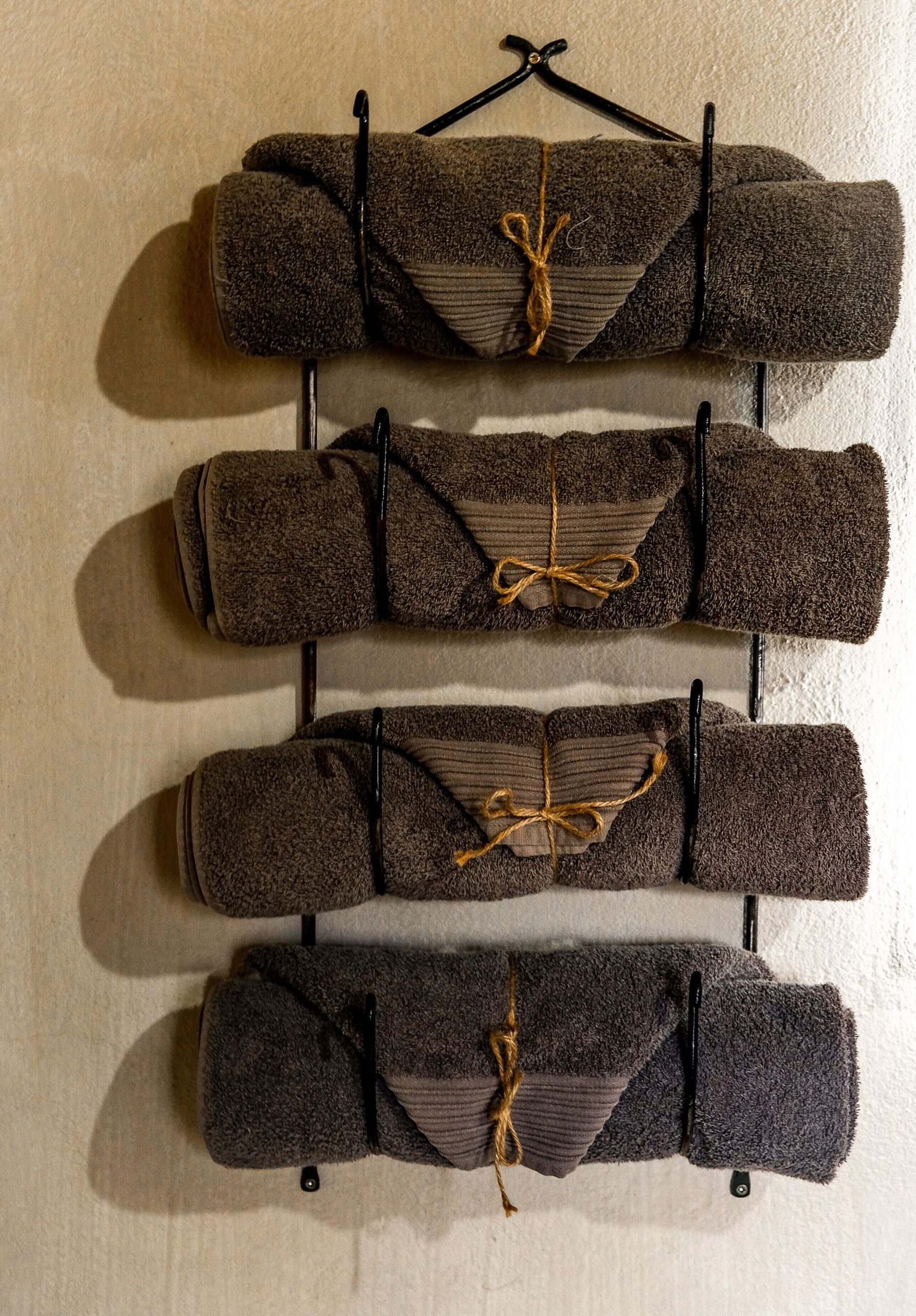 A stylish vertical arrangement of rolled towels on a decorative wall rack.
