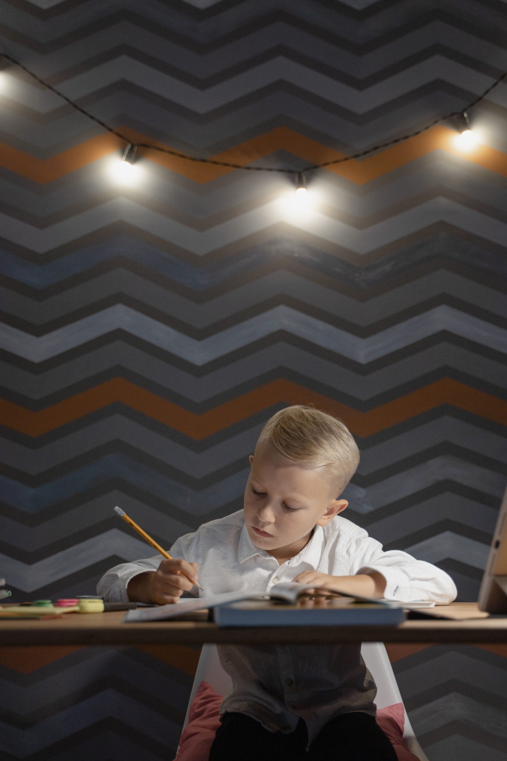 A young boy diligently doing homework at a desk under warm lights.