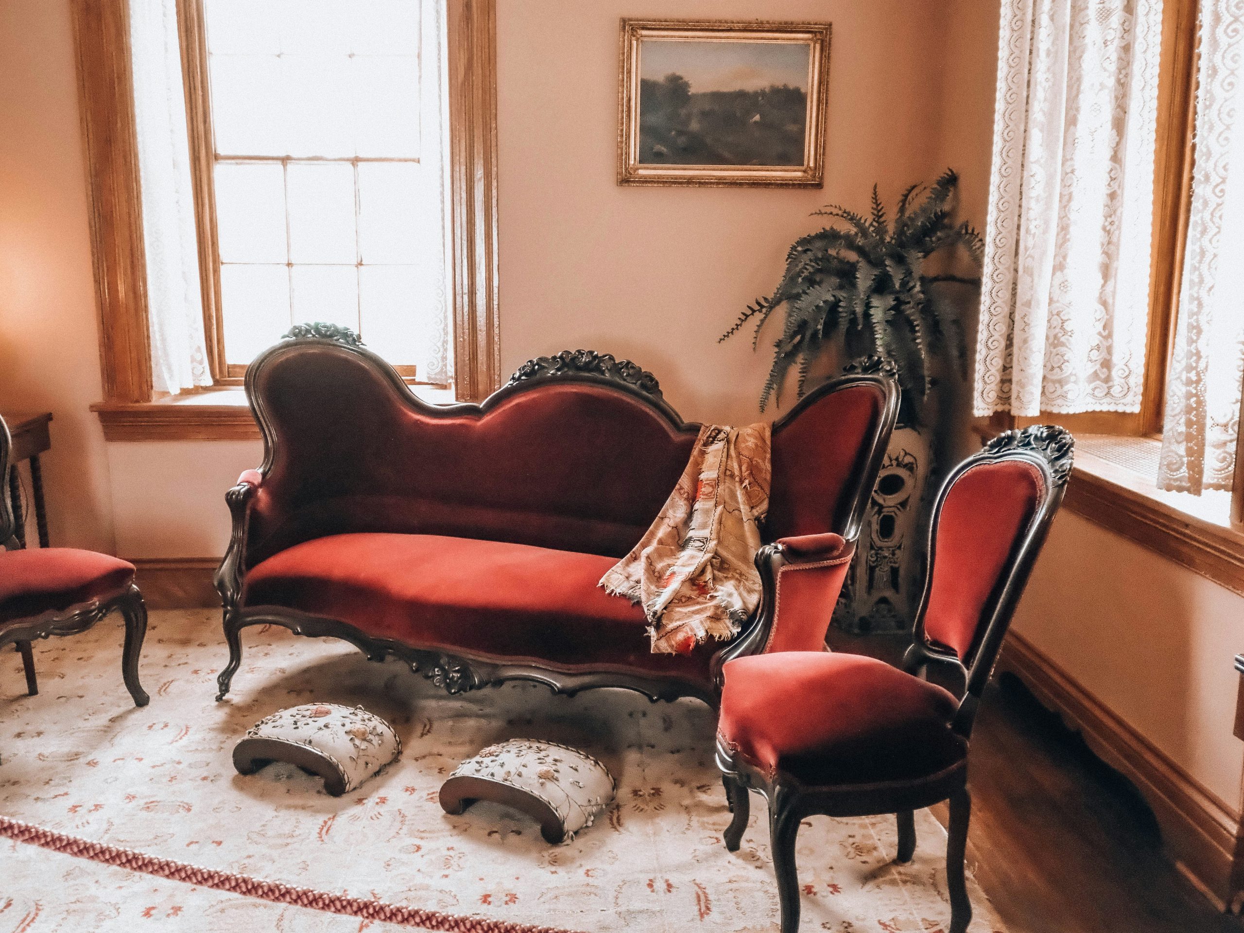 An ornate room with red velvet chaise lounge and chairs.