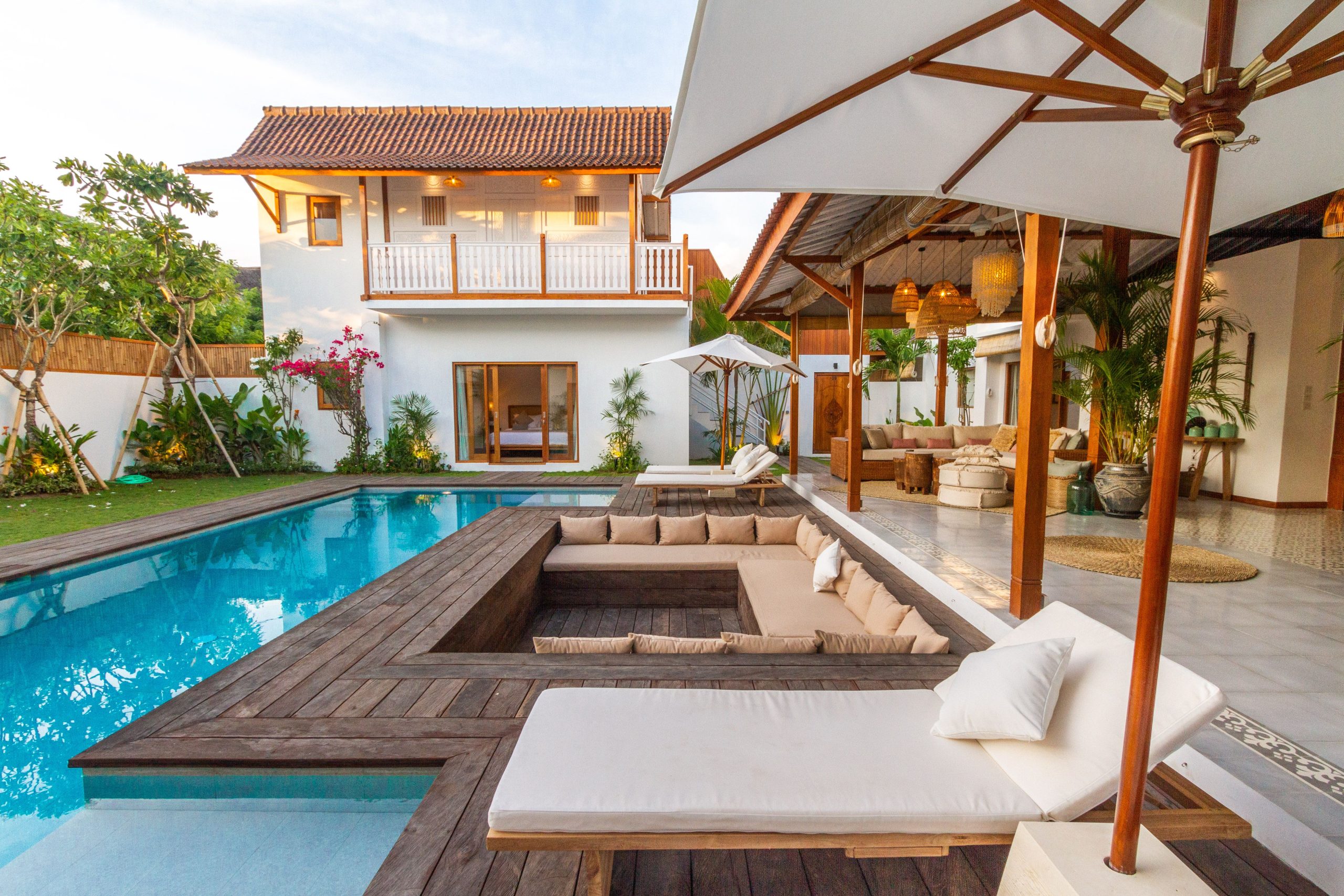 Beautiful modern villa featuring a pool, wooden deck, and lush greenery.