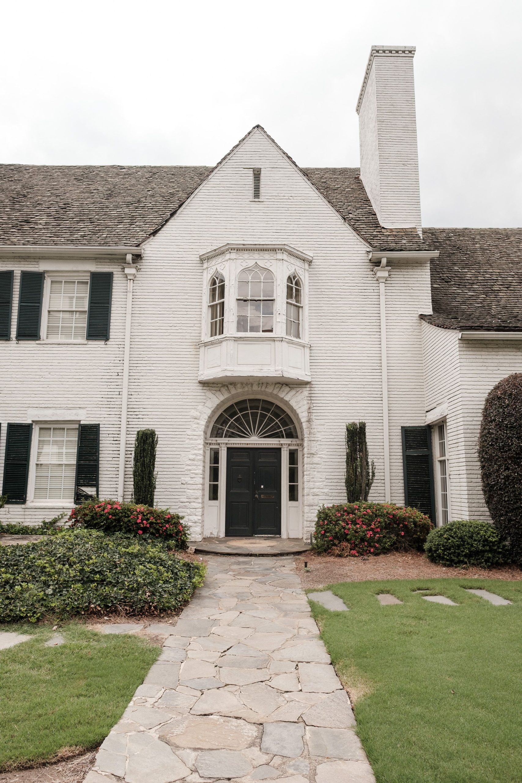 Beautiful white colonial house exterior with front door and garden pathway, perfect for architecture enthusiasts.