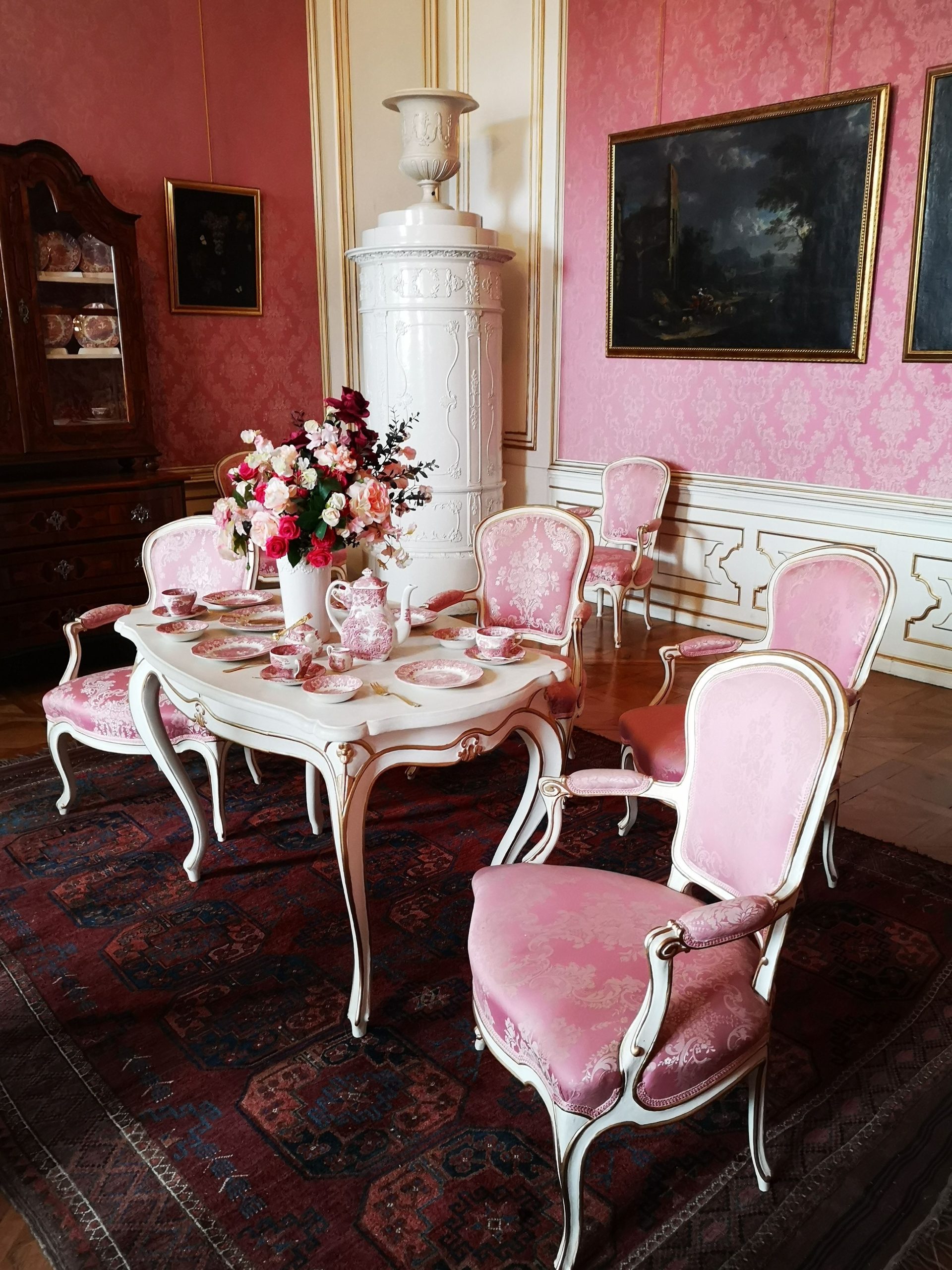 Beautifully set Victorian dining room with pink chairs and floral arrangement, exuding elegance.