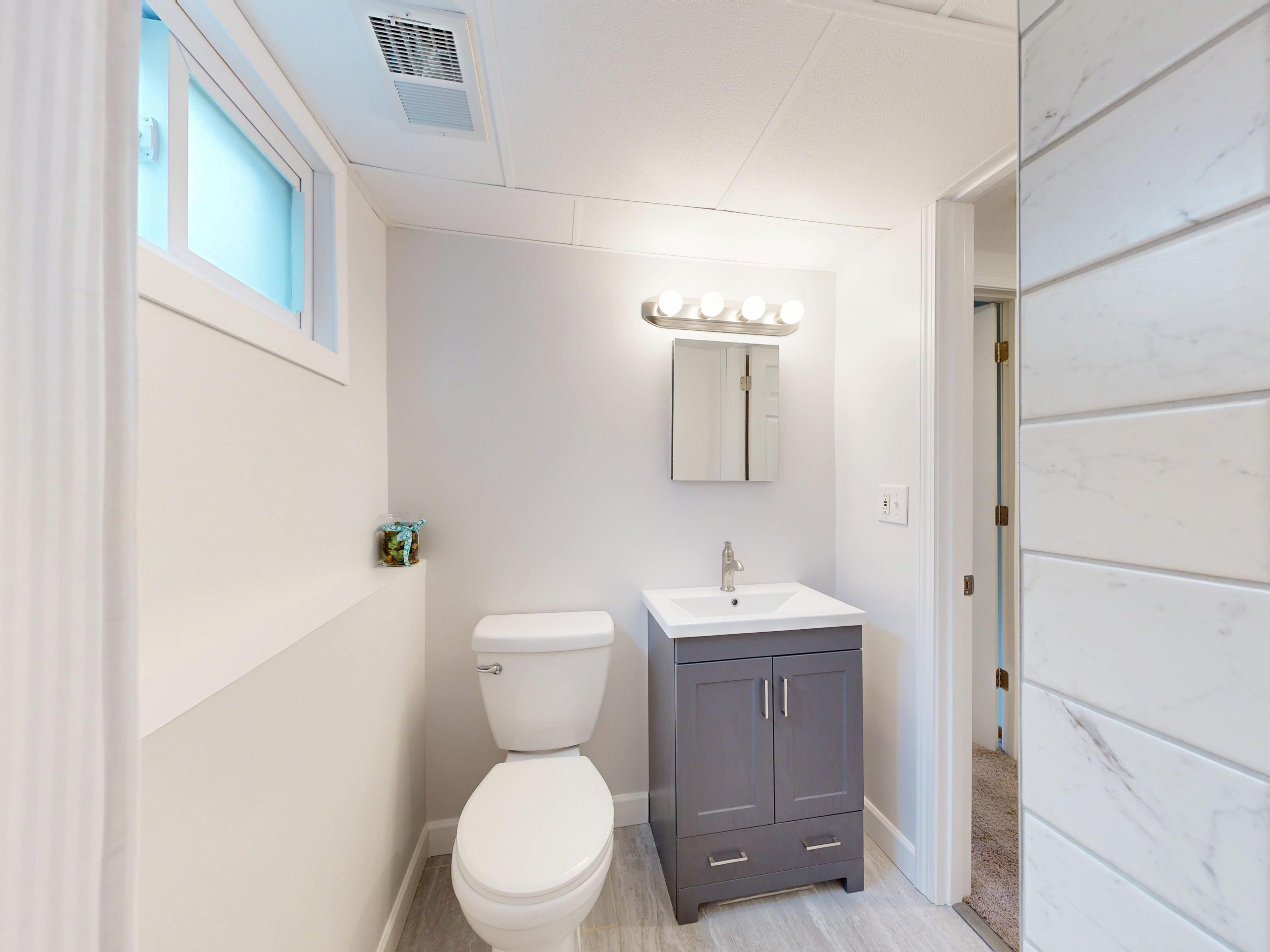 Bright modern bathroom interior with vanity, sink, and toilet in neutral colors.