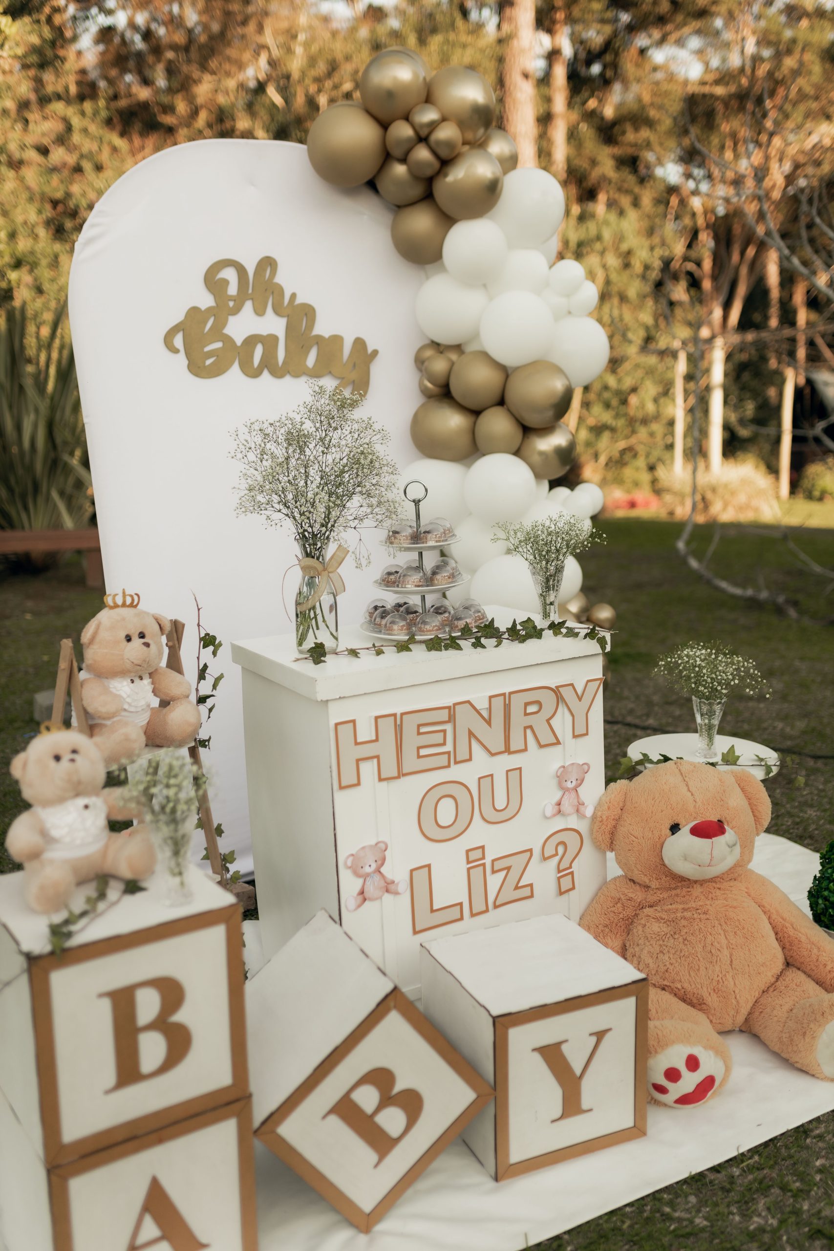 Charming gender reveal setup featuring teddy bears and balloons with gold and white theme.