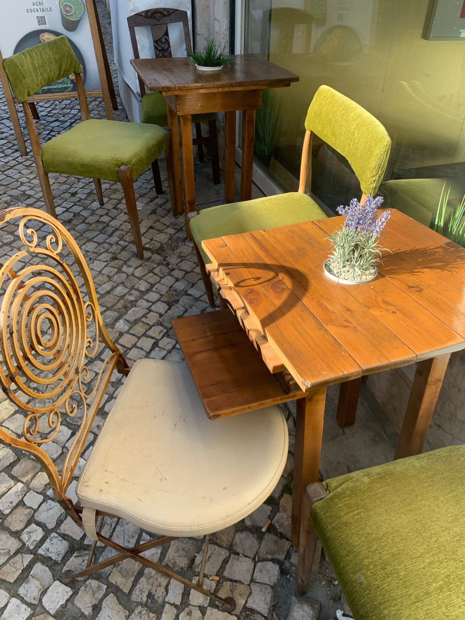 Charming outdoor cafe setting featuring vintage chairs and tables on a cobblestone street.