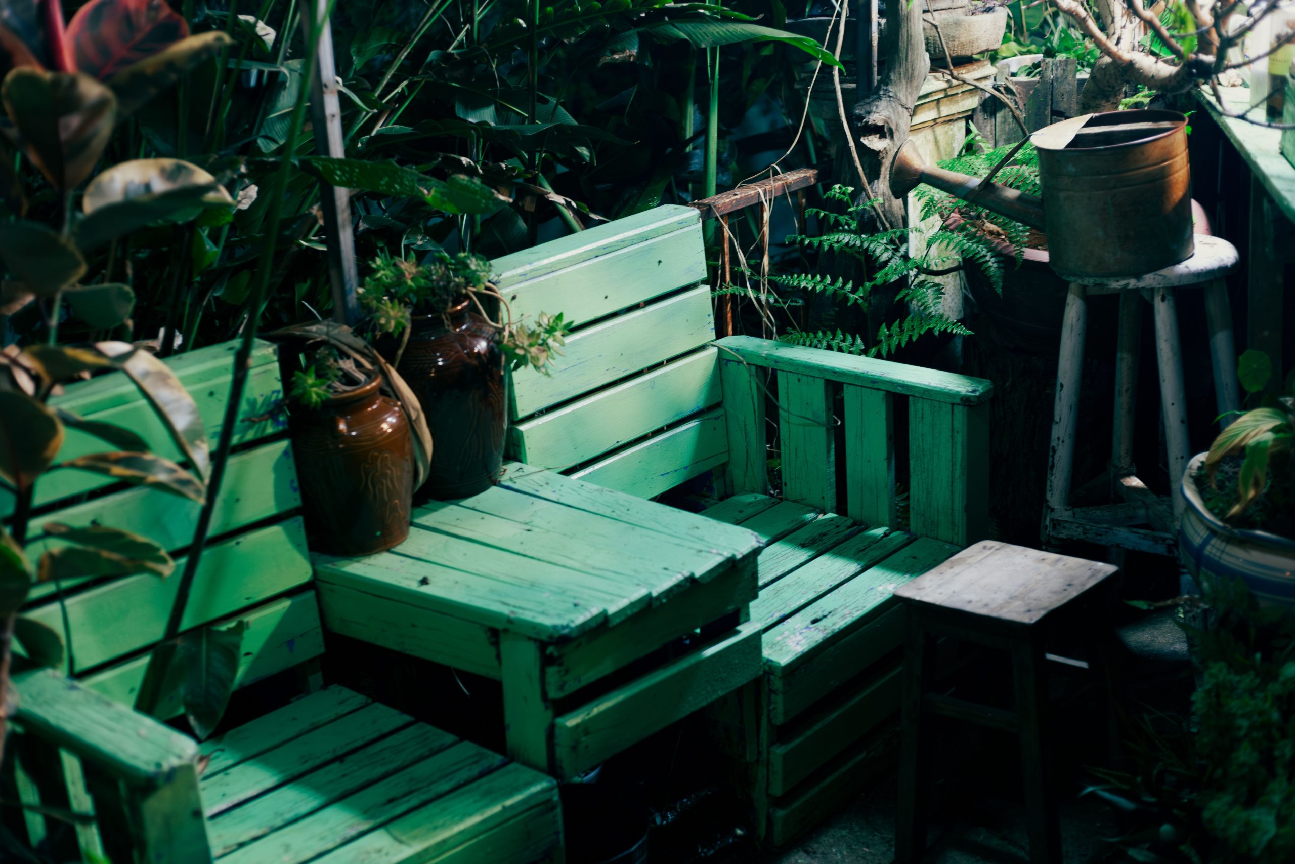 Charming outdoor garden seating area with green pallets and vintage watering can.