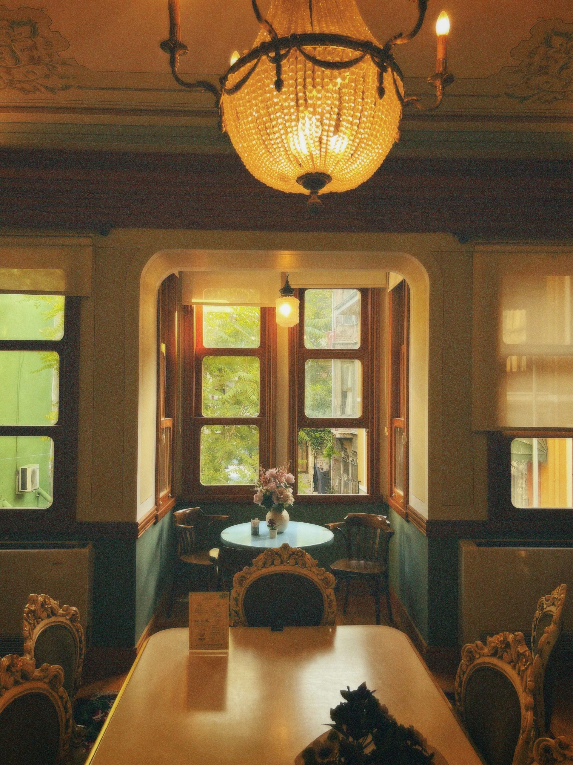 Charming vintage dining room with chandelier, table, chairs, and window view.