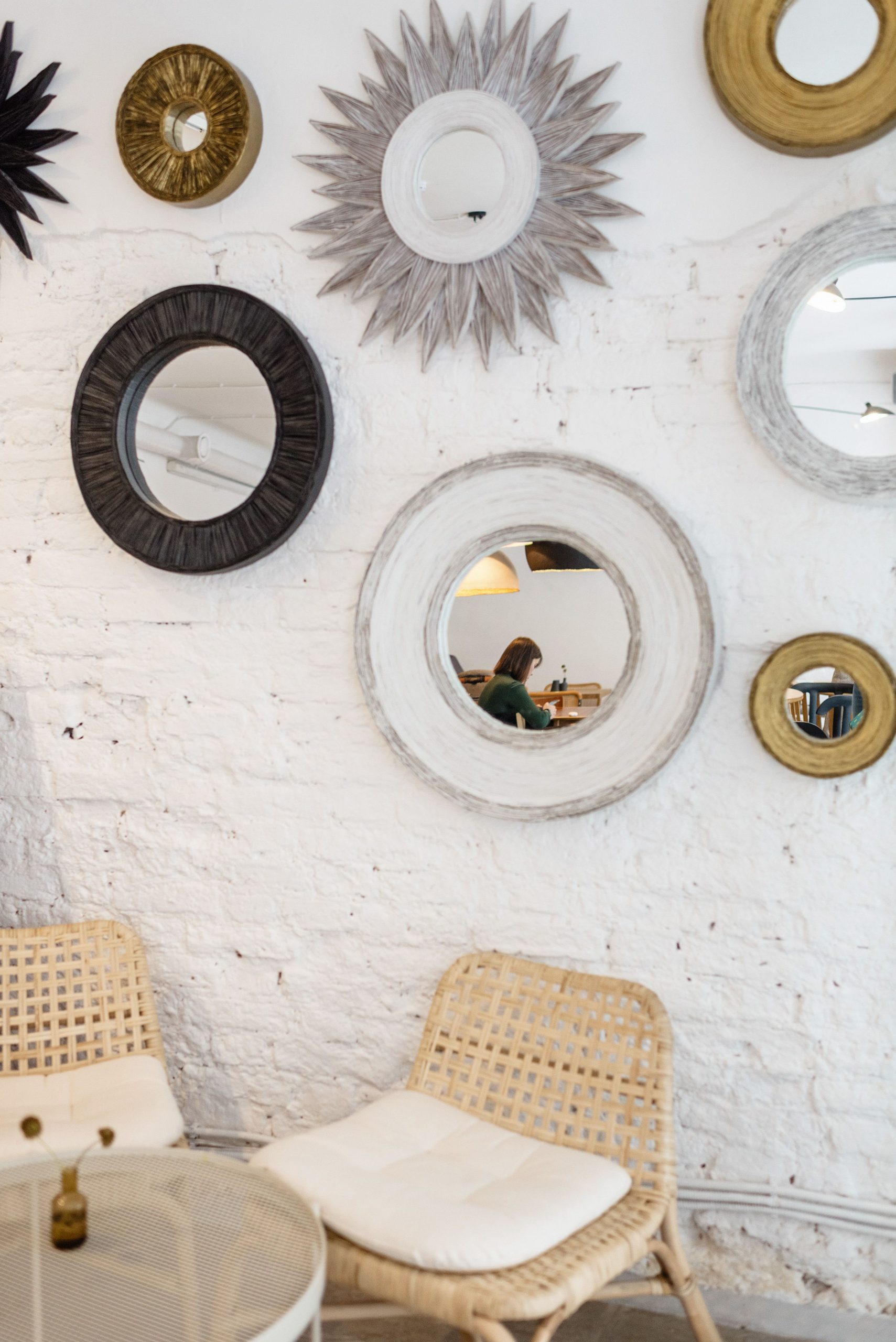 Chic interior featuring a wall adorned with decorative mirrors and wicker chairs