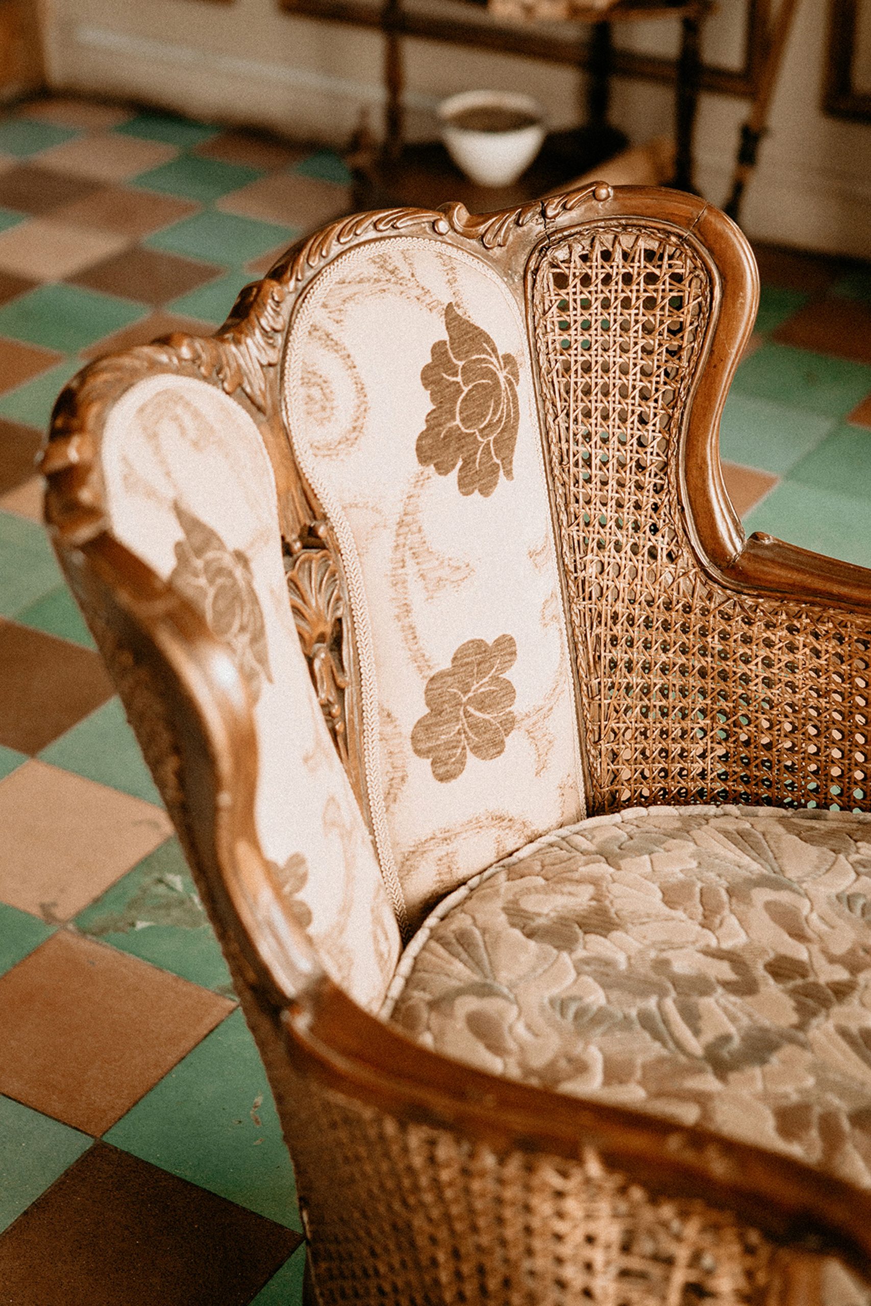 Close-up view of a vintage wooden armchair with a floral pattern, showcasing intricate woodwork.