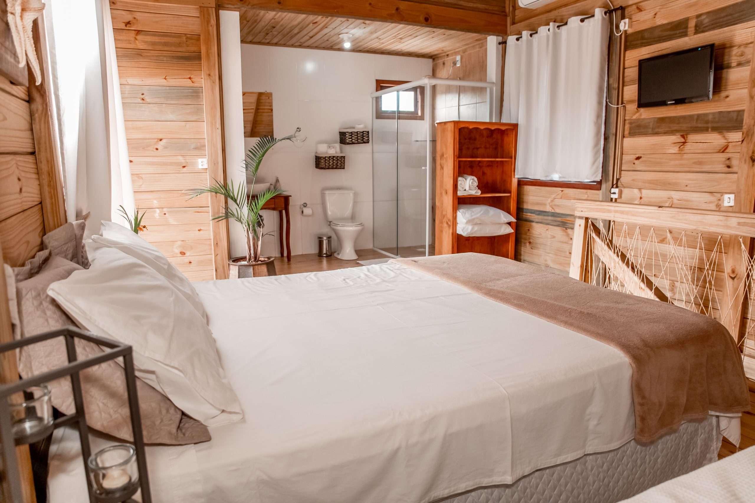 Comfortable bedroom with wooden decor, white bedding, ensuite bathroom, and modern amenities.