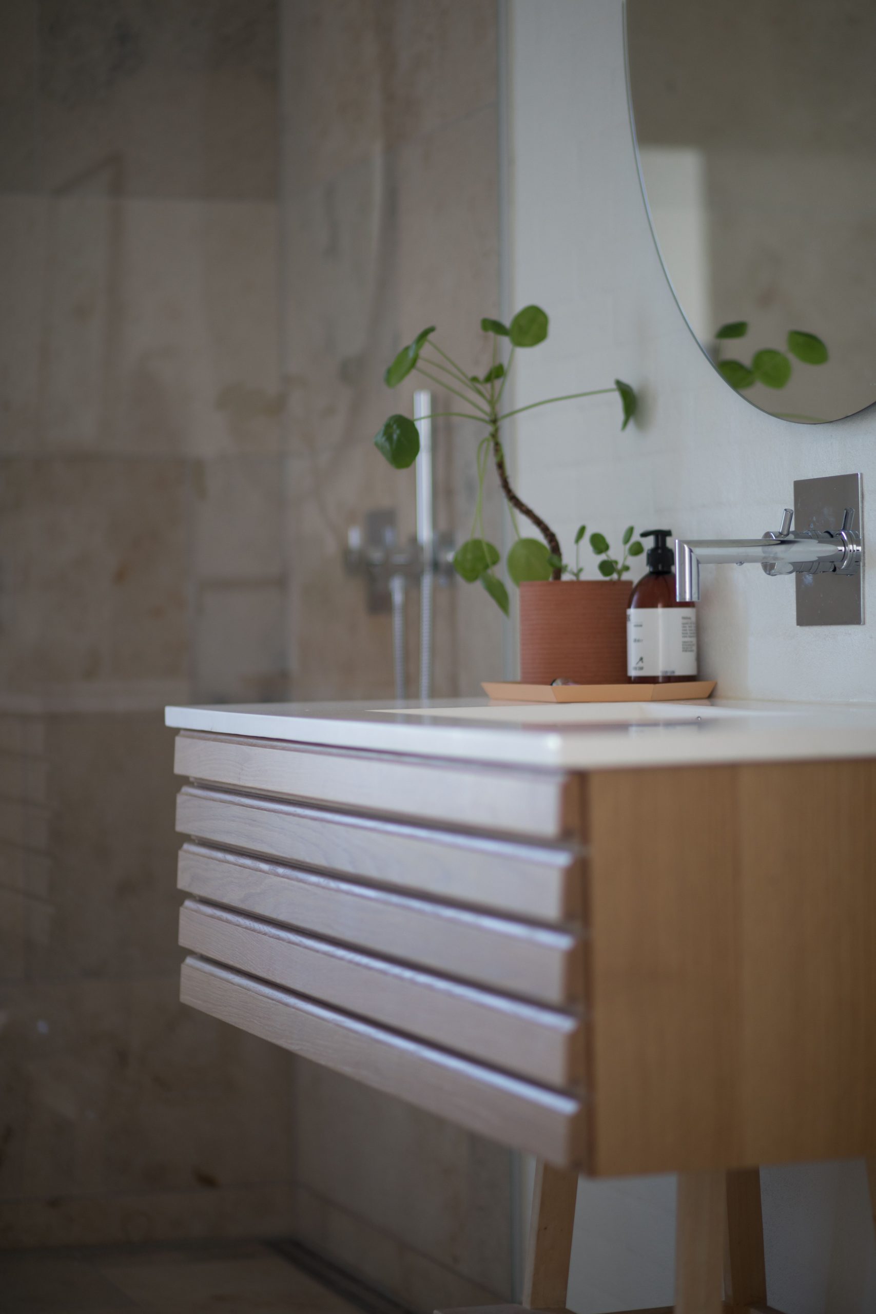Contemporary bathroom featuring a sleek sink, wooden vanity, and green potted plant decor.