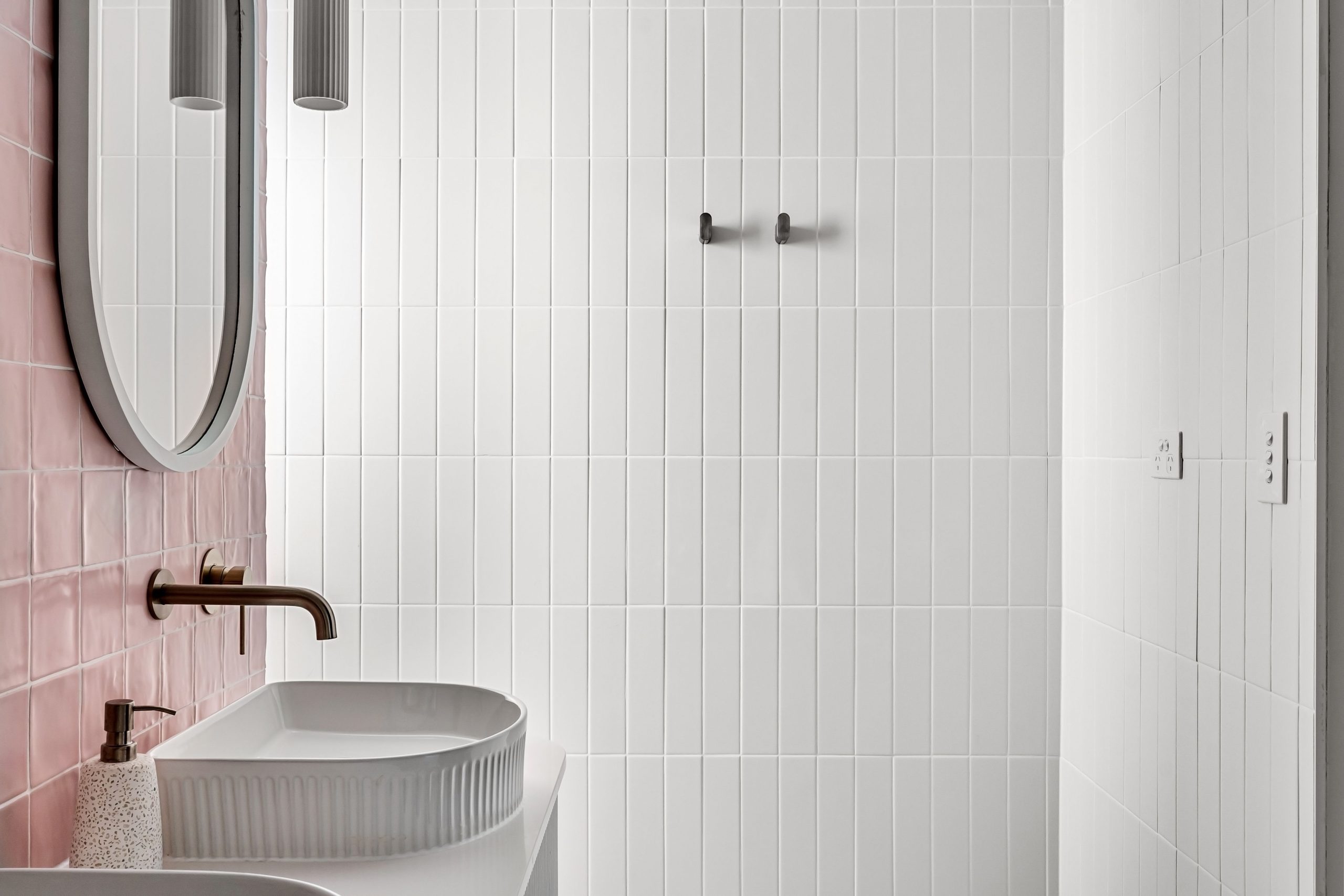 Contemporary bathroom featuring minimalist design with pink and white tiles and a sleek faucet.