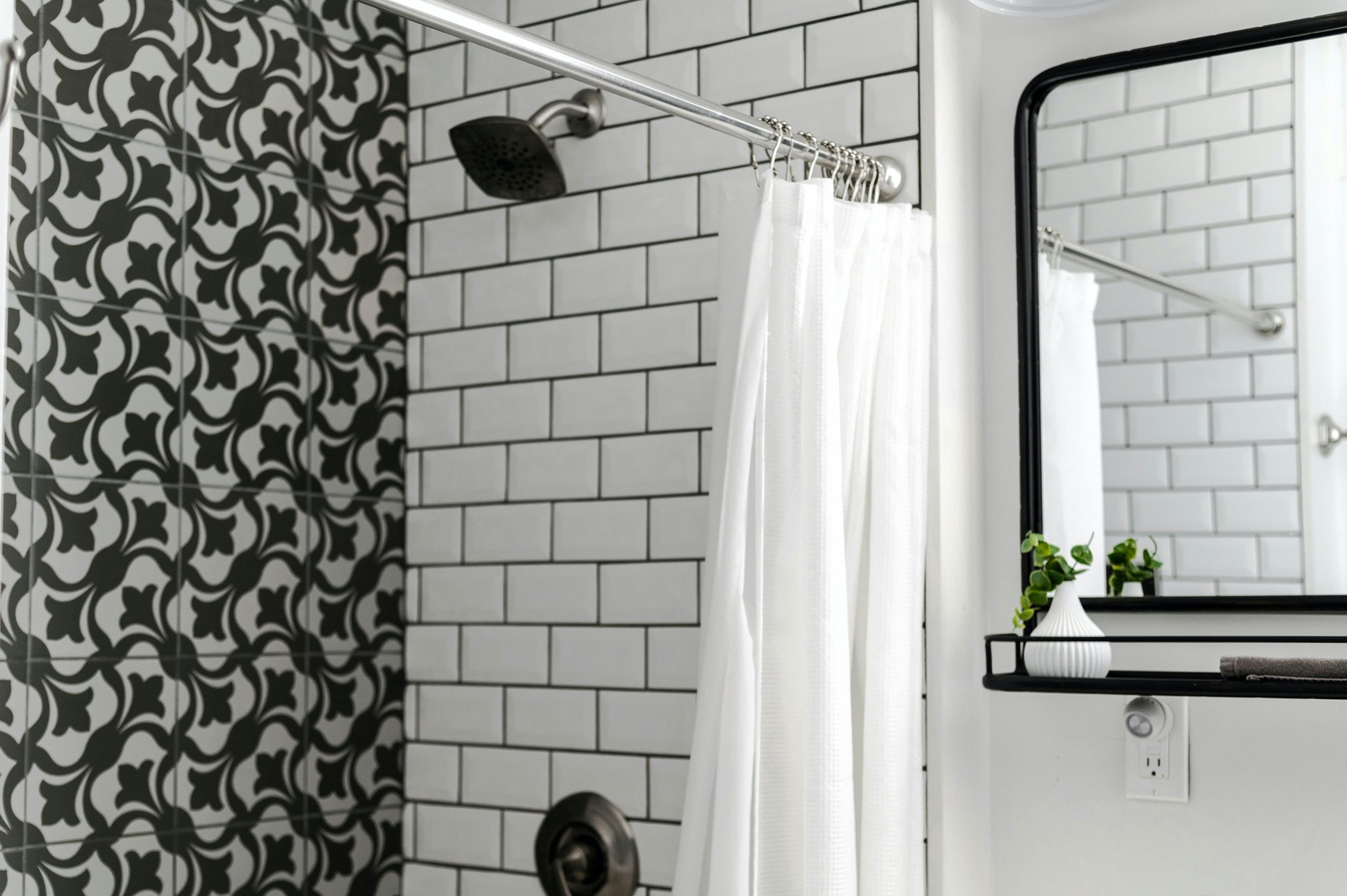 Contemporary bathroom featuring patterned and subway tiles with a minimalist mirror and white shower curtain.