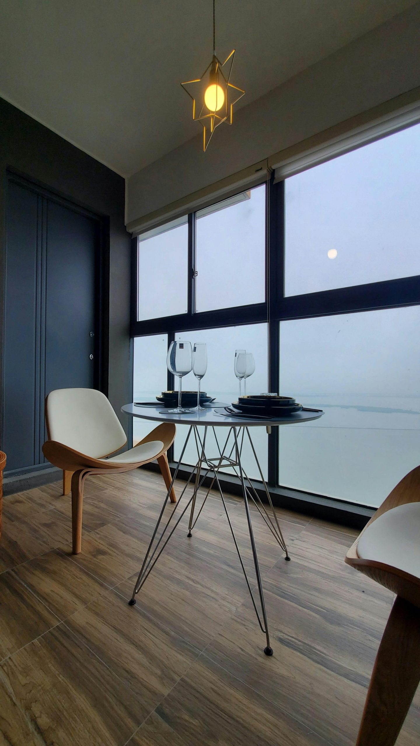 Contemporary dining setup with chairs, table, and ocean view from a window.