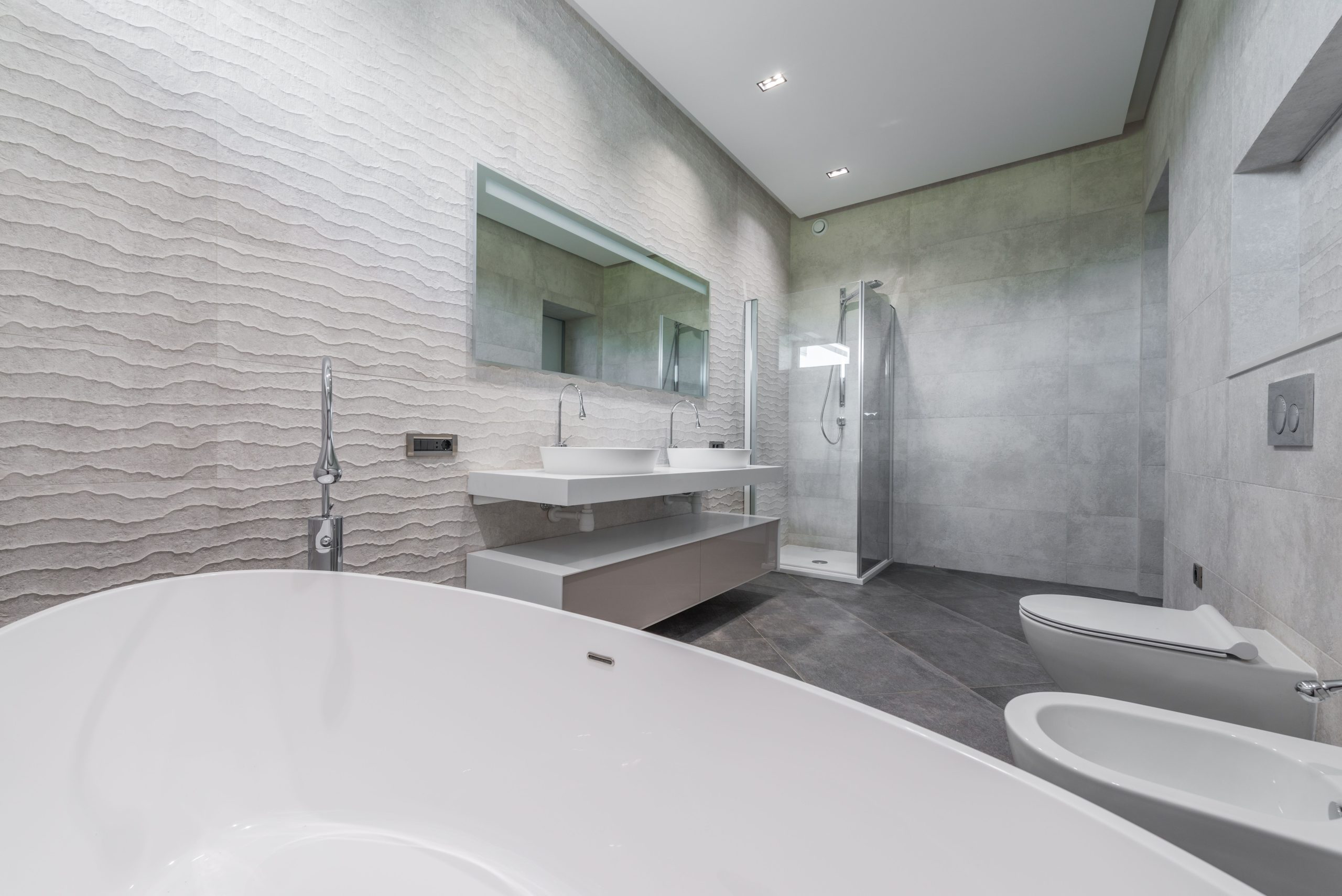 Contemporary minimalist luxury interior design of light bathroom with gray walls and floor furnished with double washbasin and bathtub in modern house