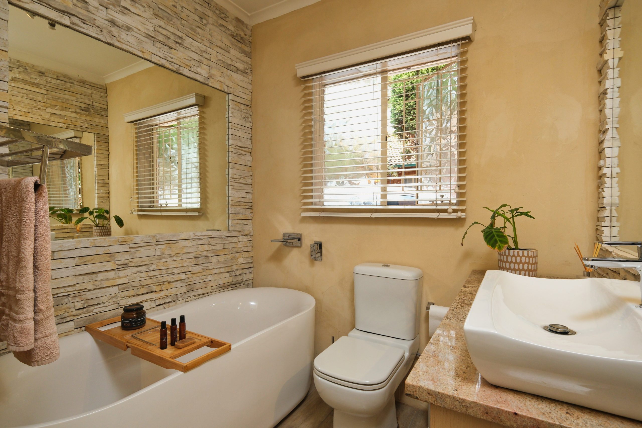 Cozy and elegant bathroom interior featuring a bathtub, sink, and natural stone wall decor.