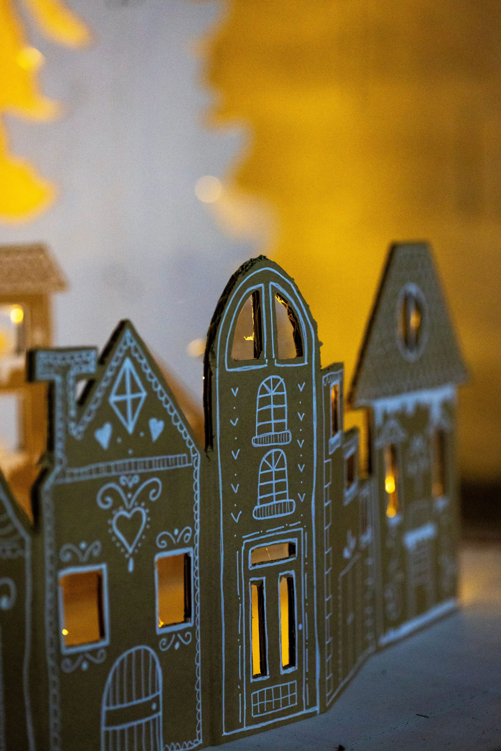 Cozy cardboard houses with intricate designs illuminated by warm ambient lighting, perfect for festive decor.