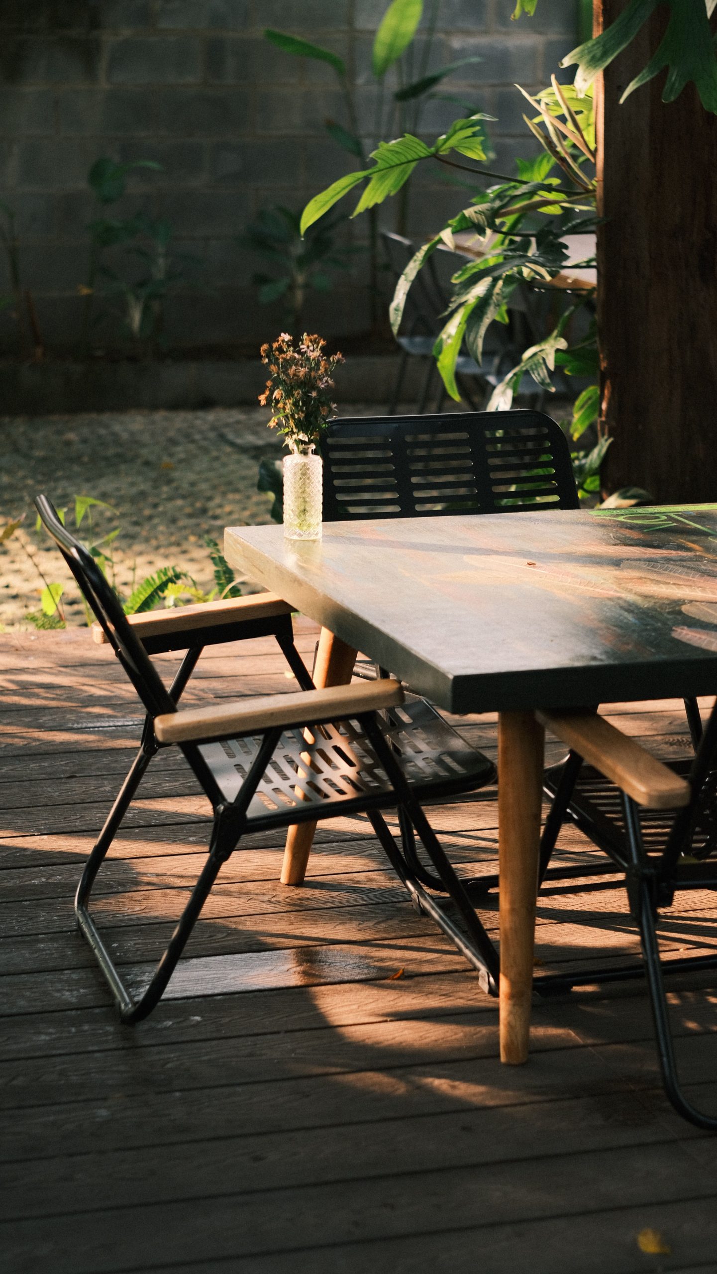 Cozy outdoor patio setting with a wooden table and chairs, beautifully illuminated by sunlight.