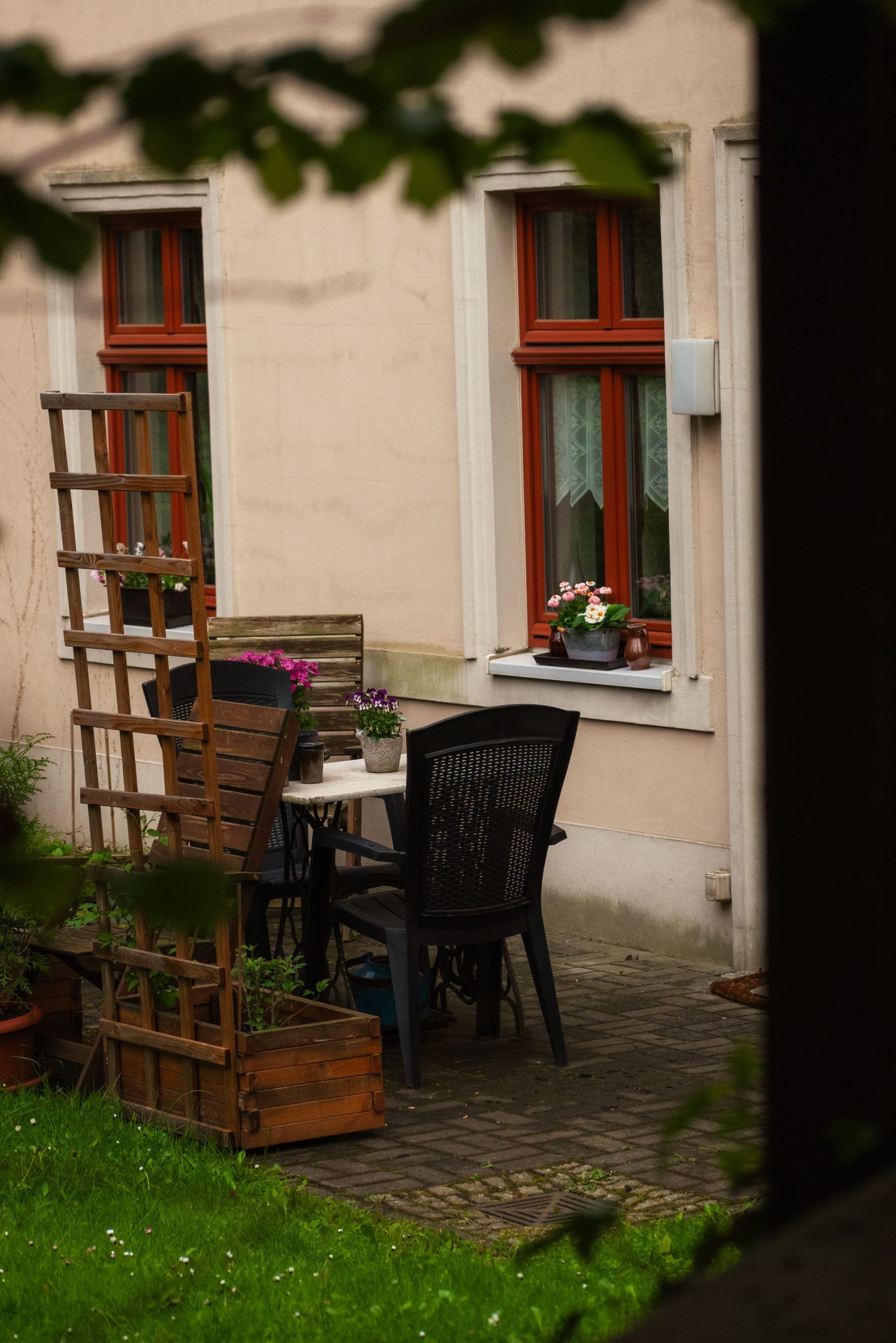 Cozy patio with wooden furniture and potted flowers against a rustic wall.