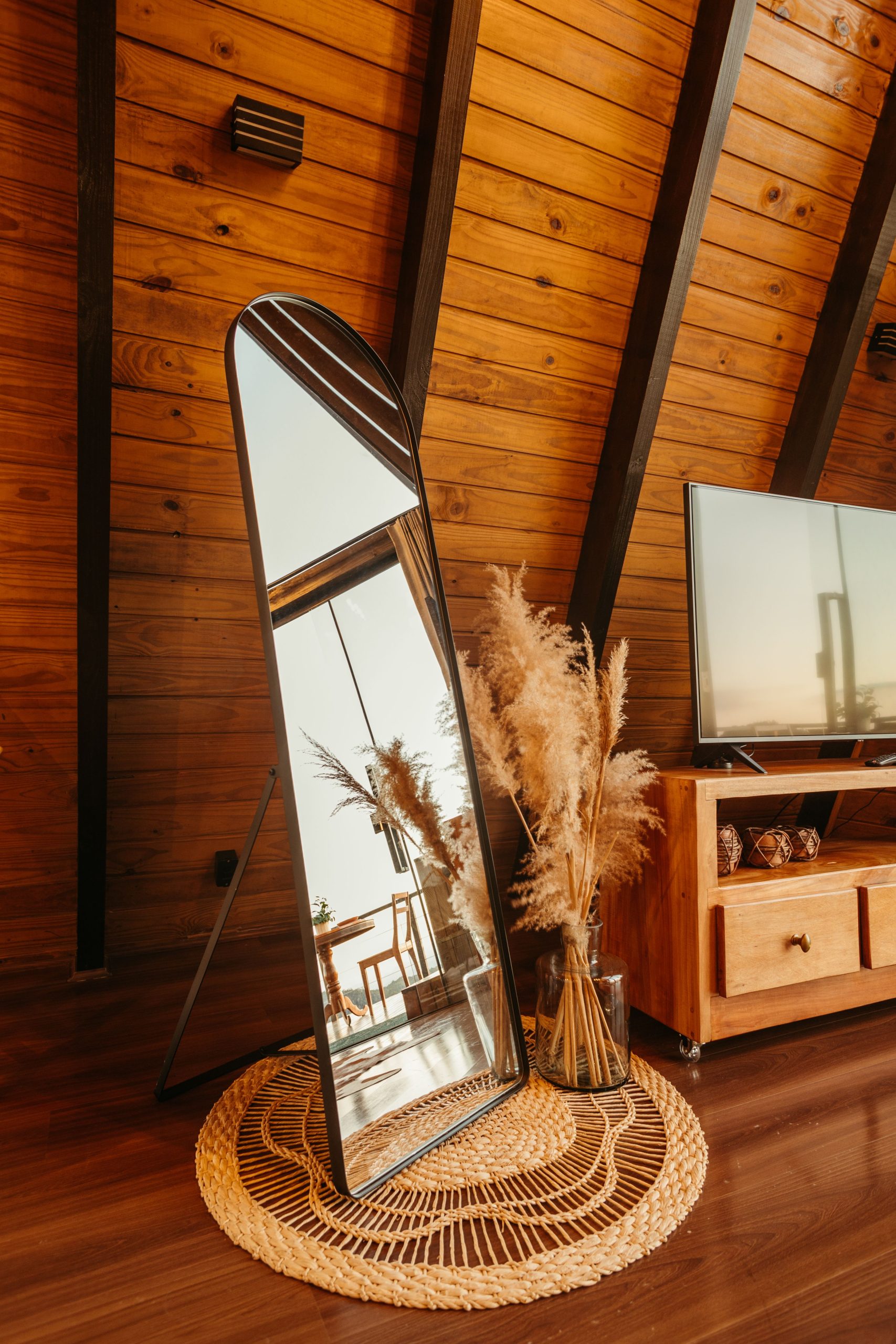 Cozy rustic room featuring a large mirror, wooden interior, and a television creating a warm atmosphere.