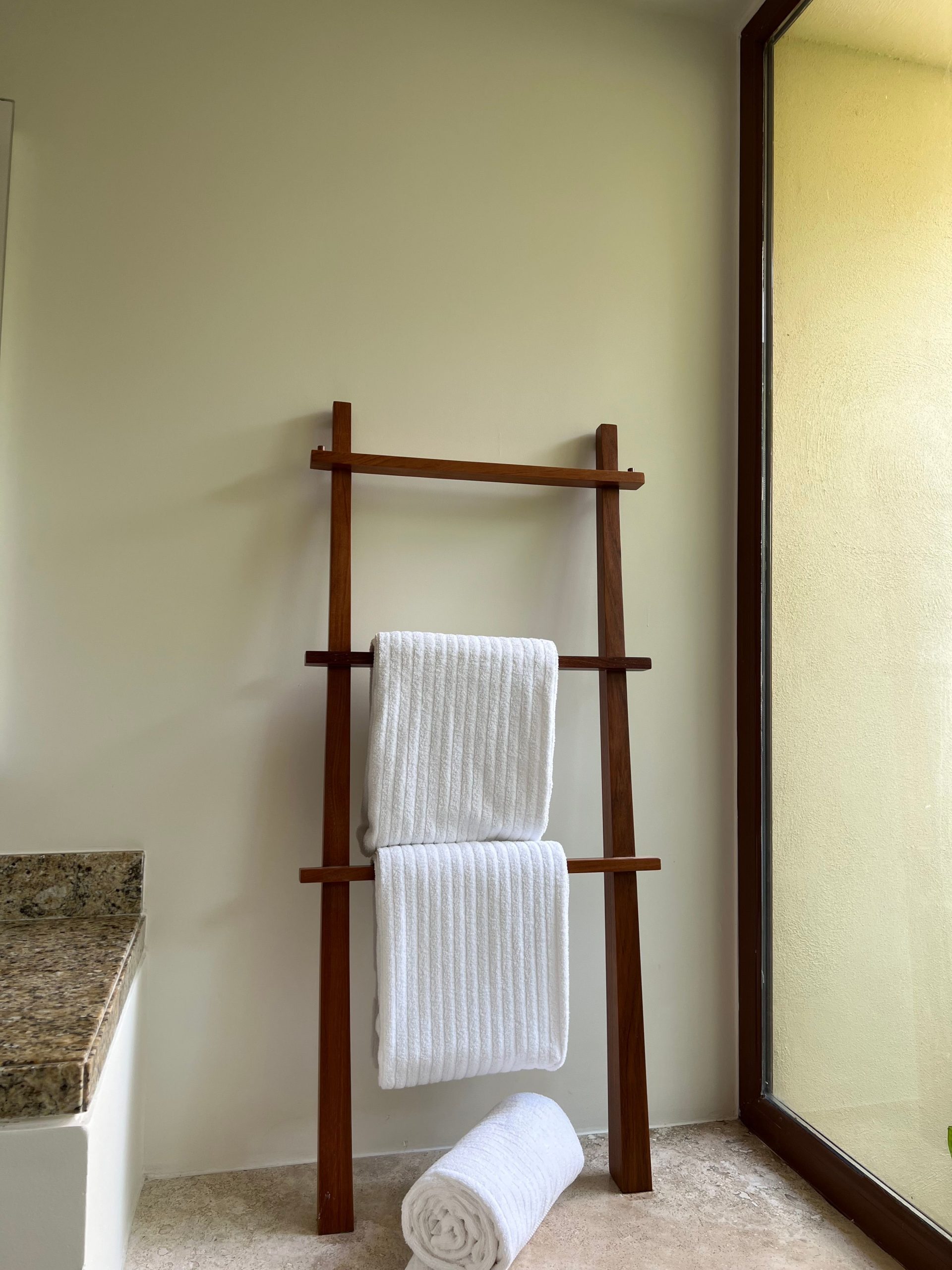 Elegant bathroom setup featuring a wooden towel rack against a light wall, providing a minimalist design.