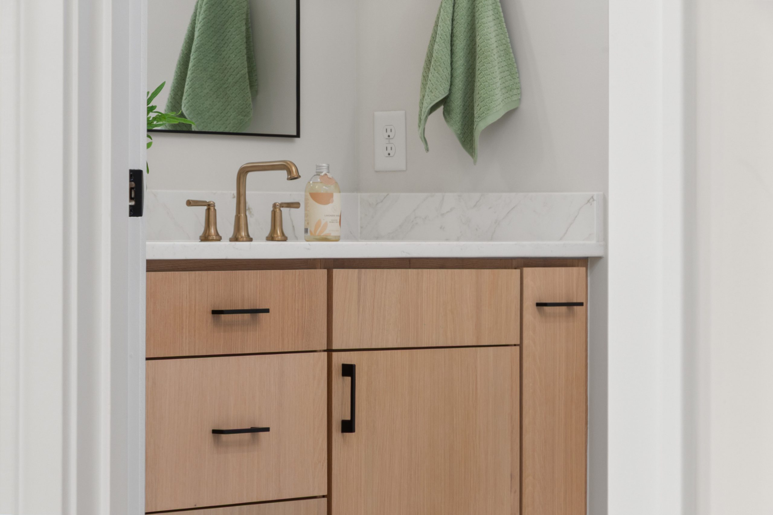 Elegant bathroom vanity featuring light wood cabinets and brass fixtures.