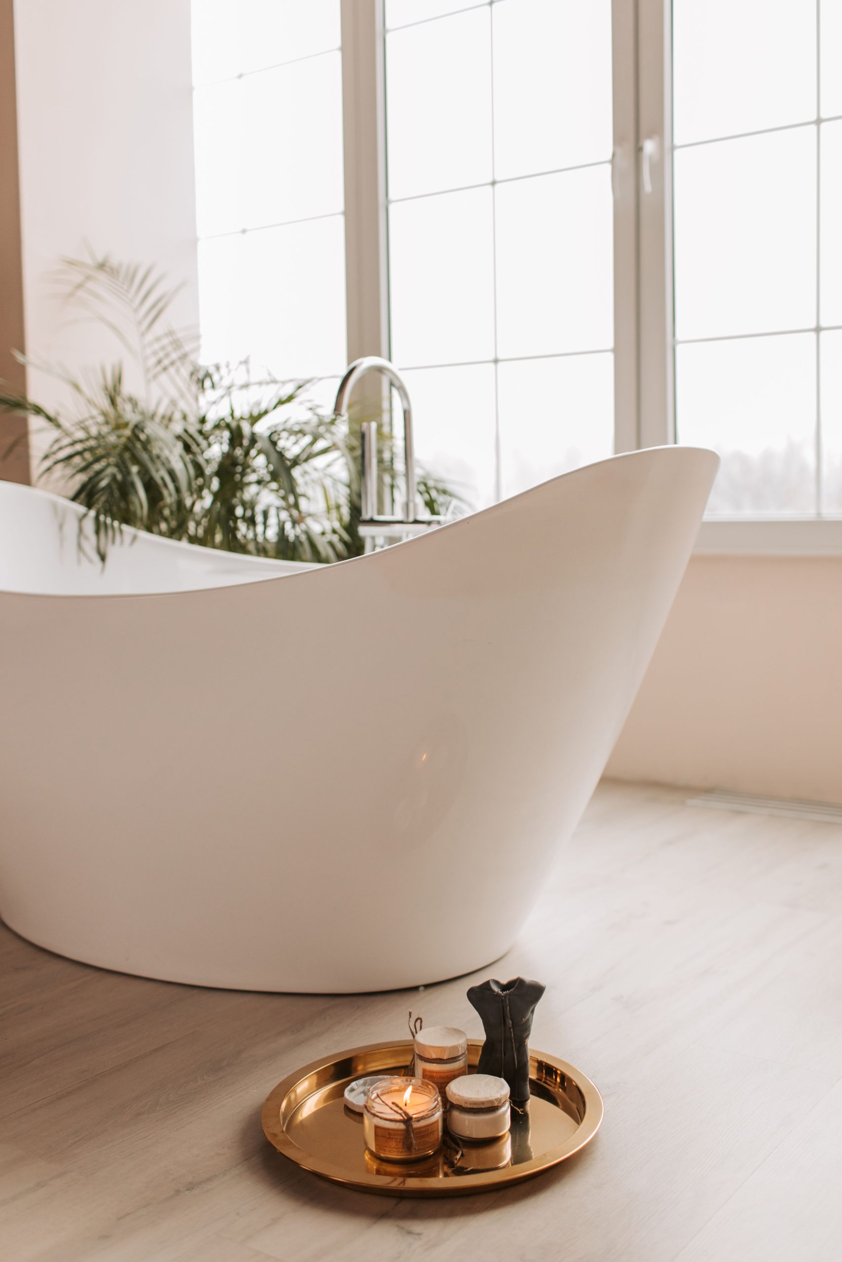 Elegant bathroom with a modern bathtub, candles, and plants, offering a serene spa-like ambiance.