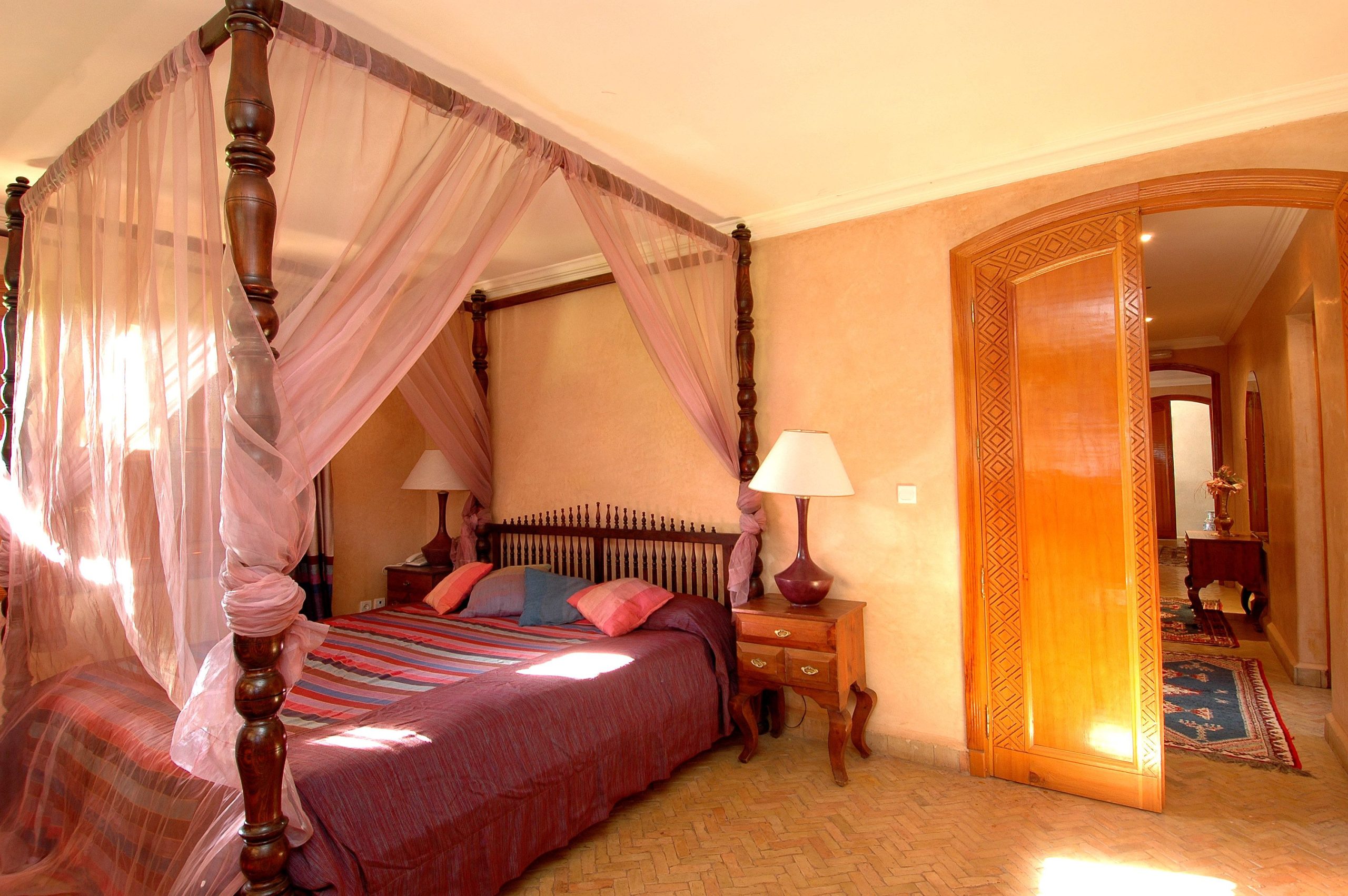 Elegant bedroom featuring a four-poster canopy bed with soft lighting and stylish furnishings.