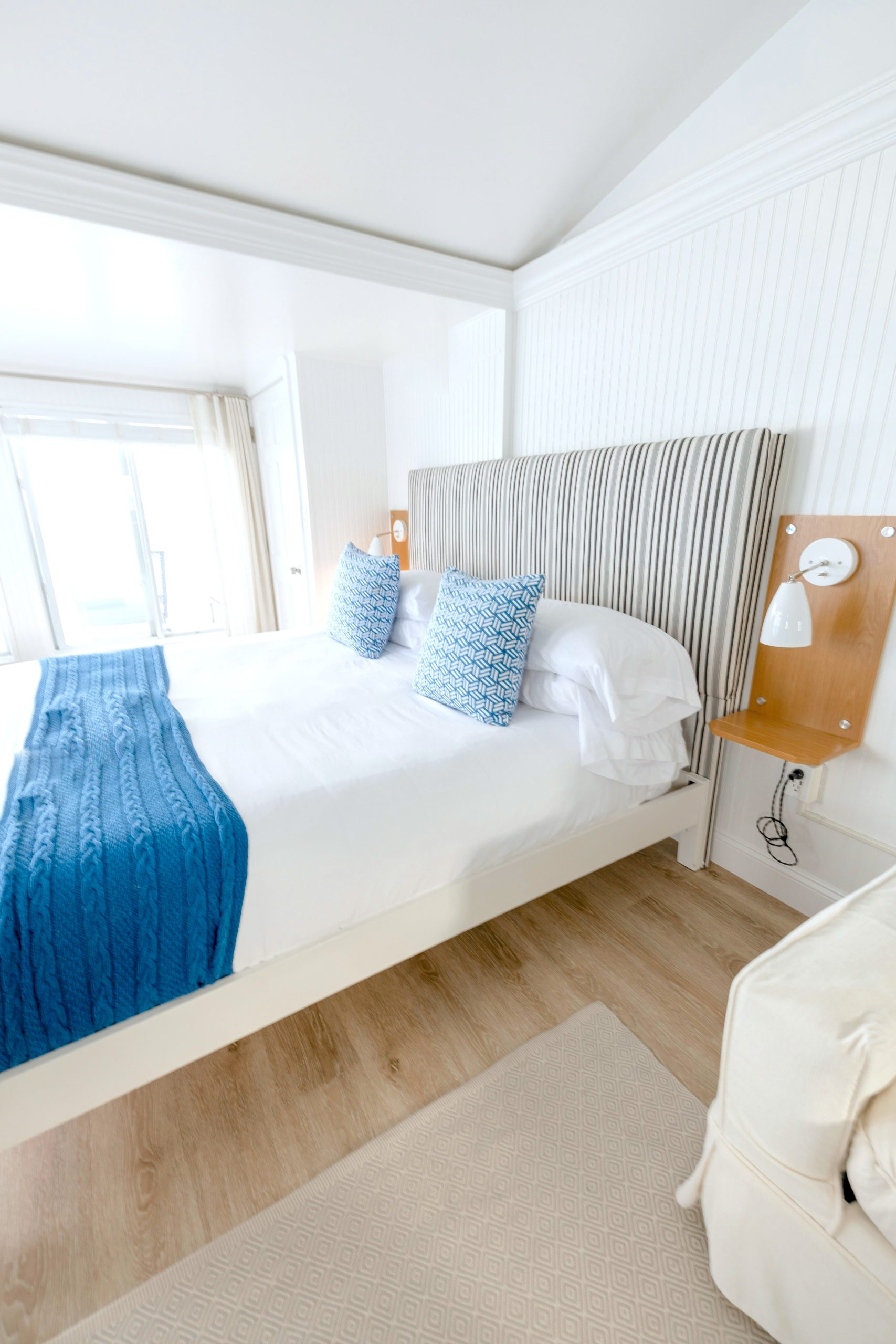 Elegant hotel room with a minimalist style featuring blue accent pillows and bedding.
