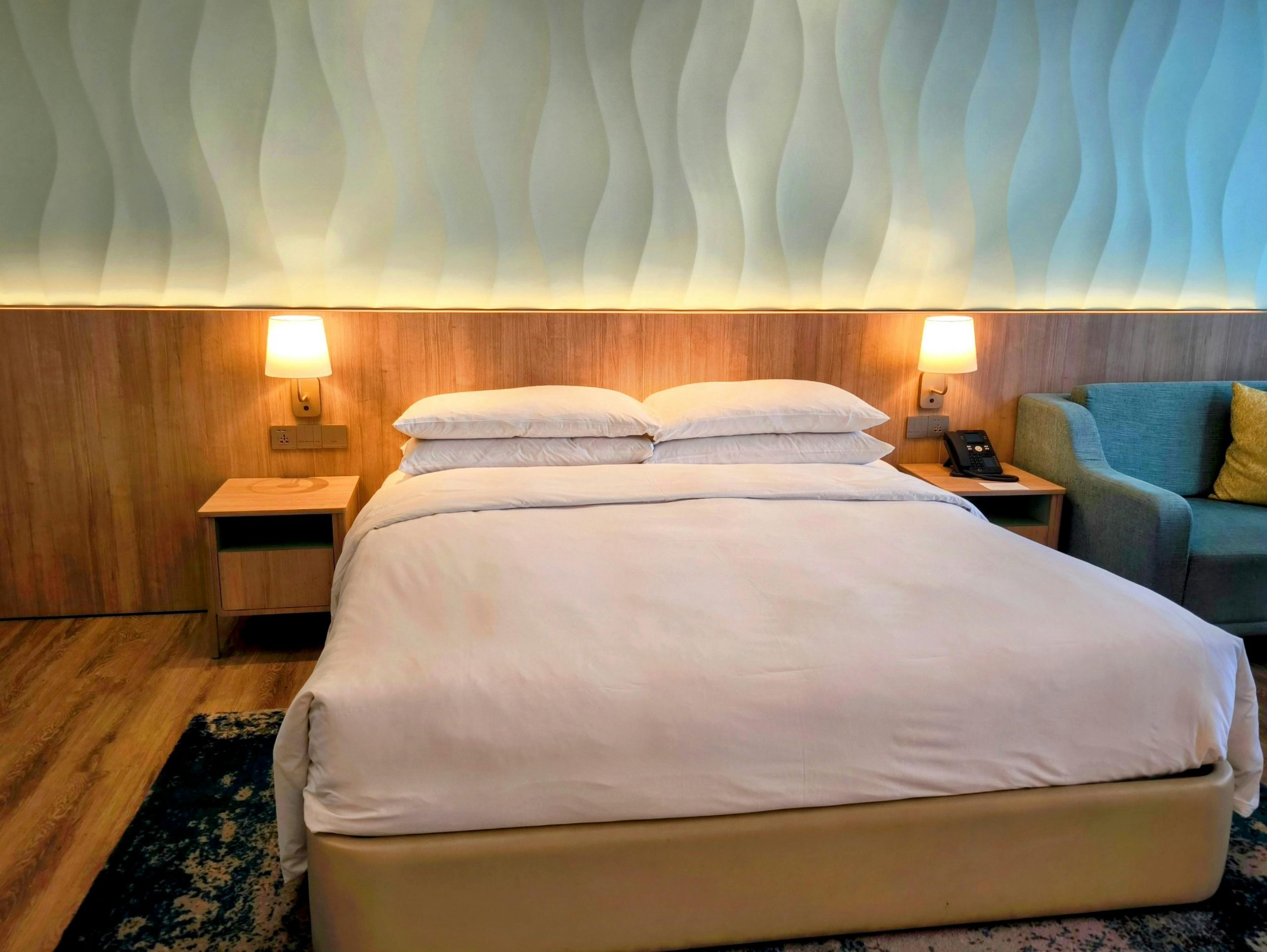 Elegant hotel room with king-size bed, stylish lighting, and cozy seating area.