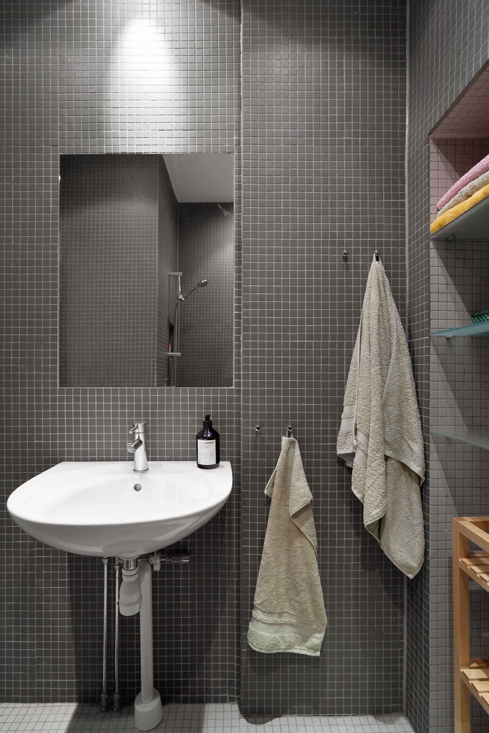 Elegant minimalist bathroom featuring a sink, mirror, and gray tiles.