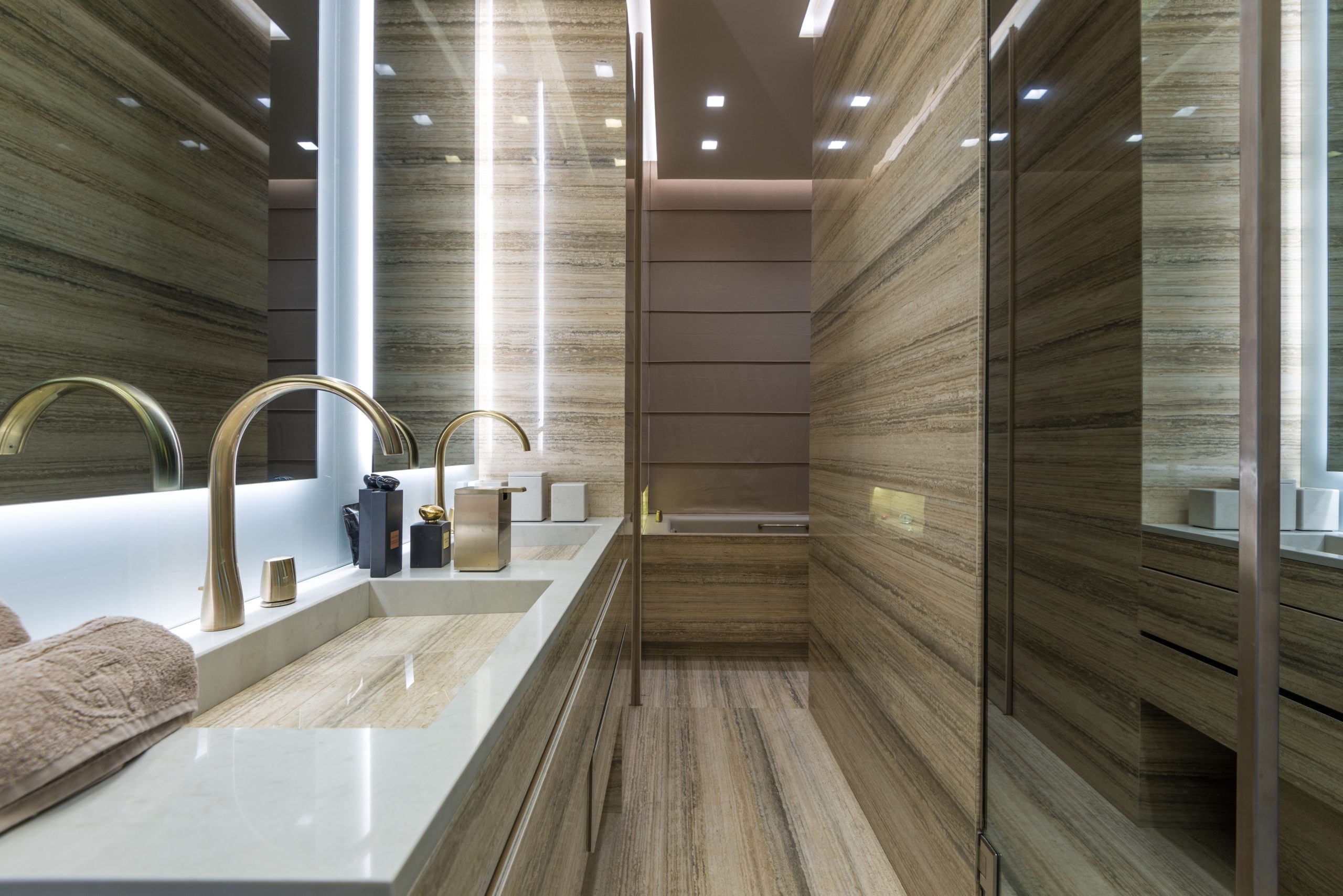 Elegant modern bathroom with marble surfaces and gold fixtures, featuring minimalistic design.