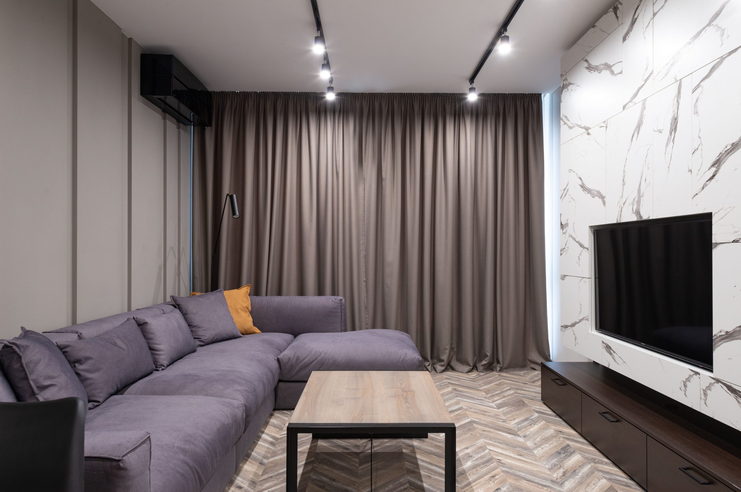 Elegant modern living room with corner sofa and minimalist decor showcasing simplicity.