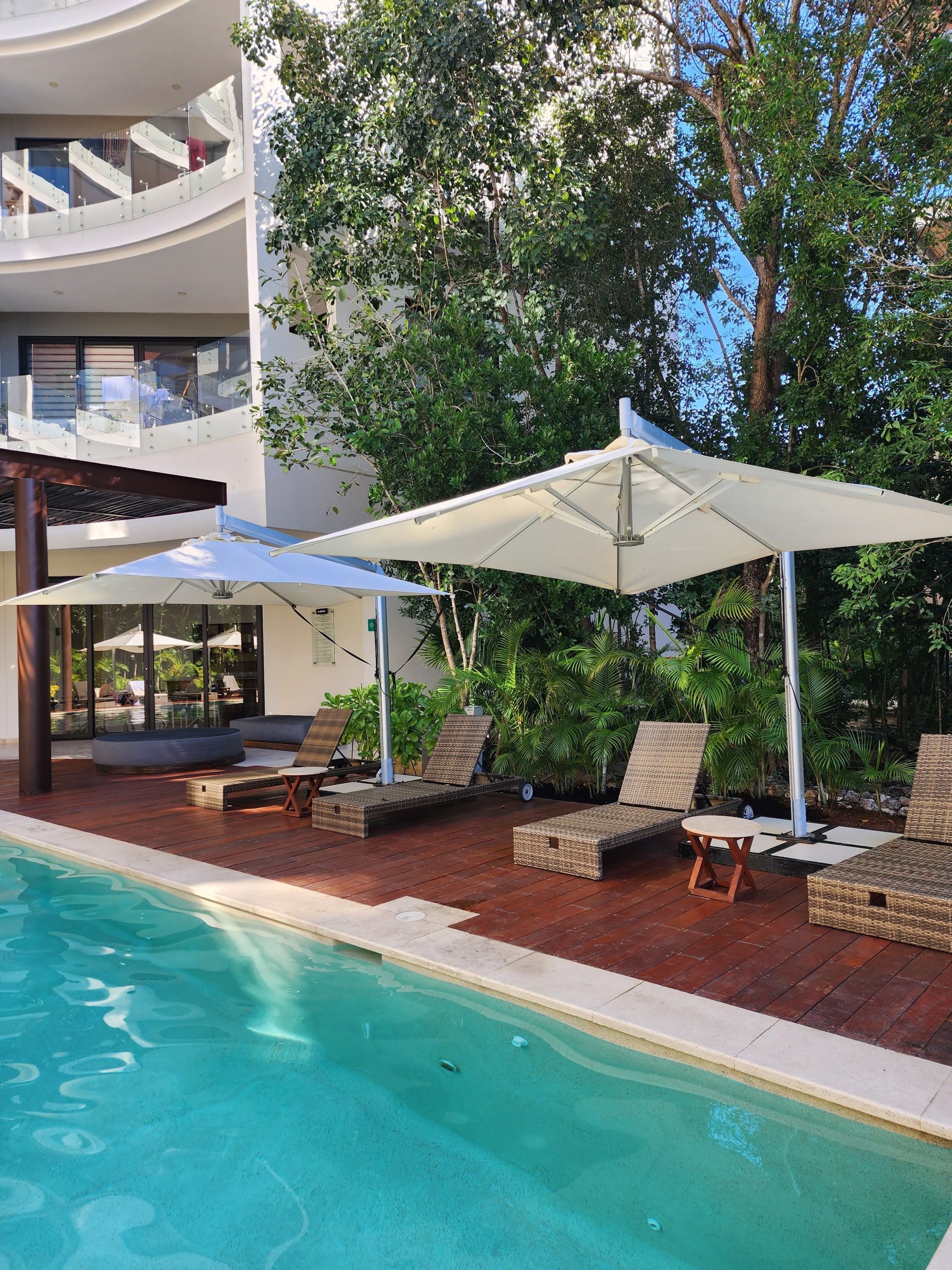 Elegant poolside setting with sun loungers and white umbrellas for relaxation.