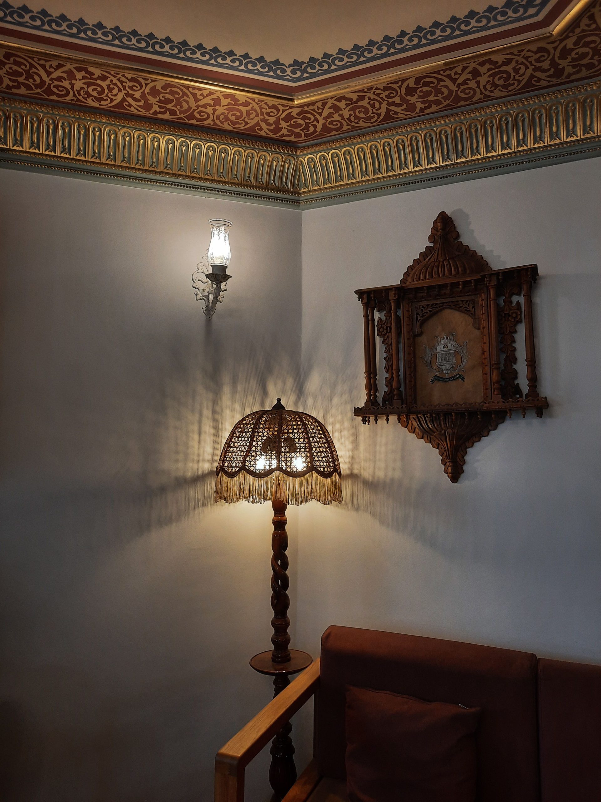 Elegant vintage corner with ornate lamp and wooden armchair, ideal for cozy interiors.