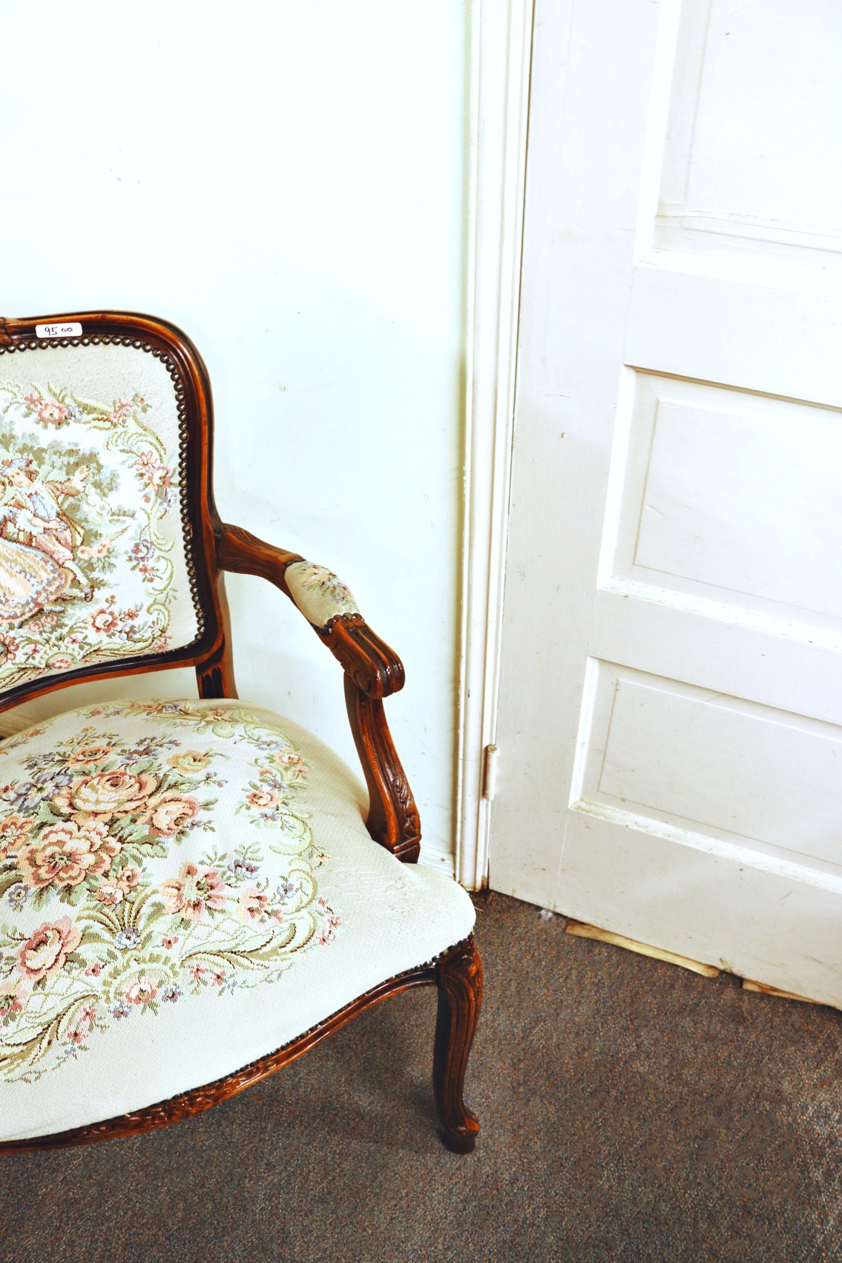 Elegant vintage floral armchair in home interior with wooden details and soft upholstery.