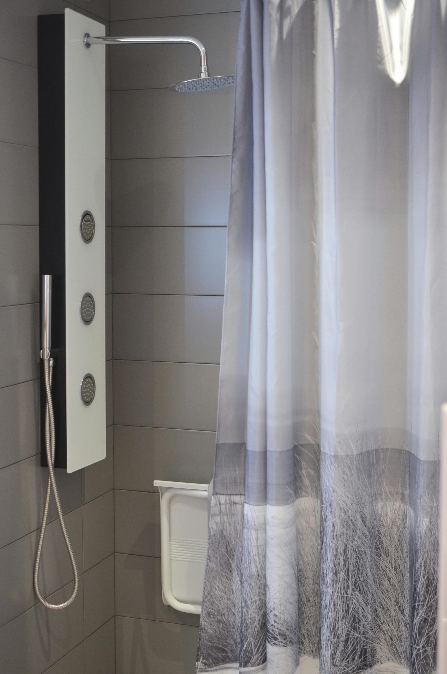 Interior of bathroom with modern shower cabin with curtains and gray tiled walls