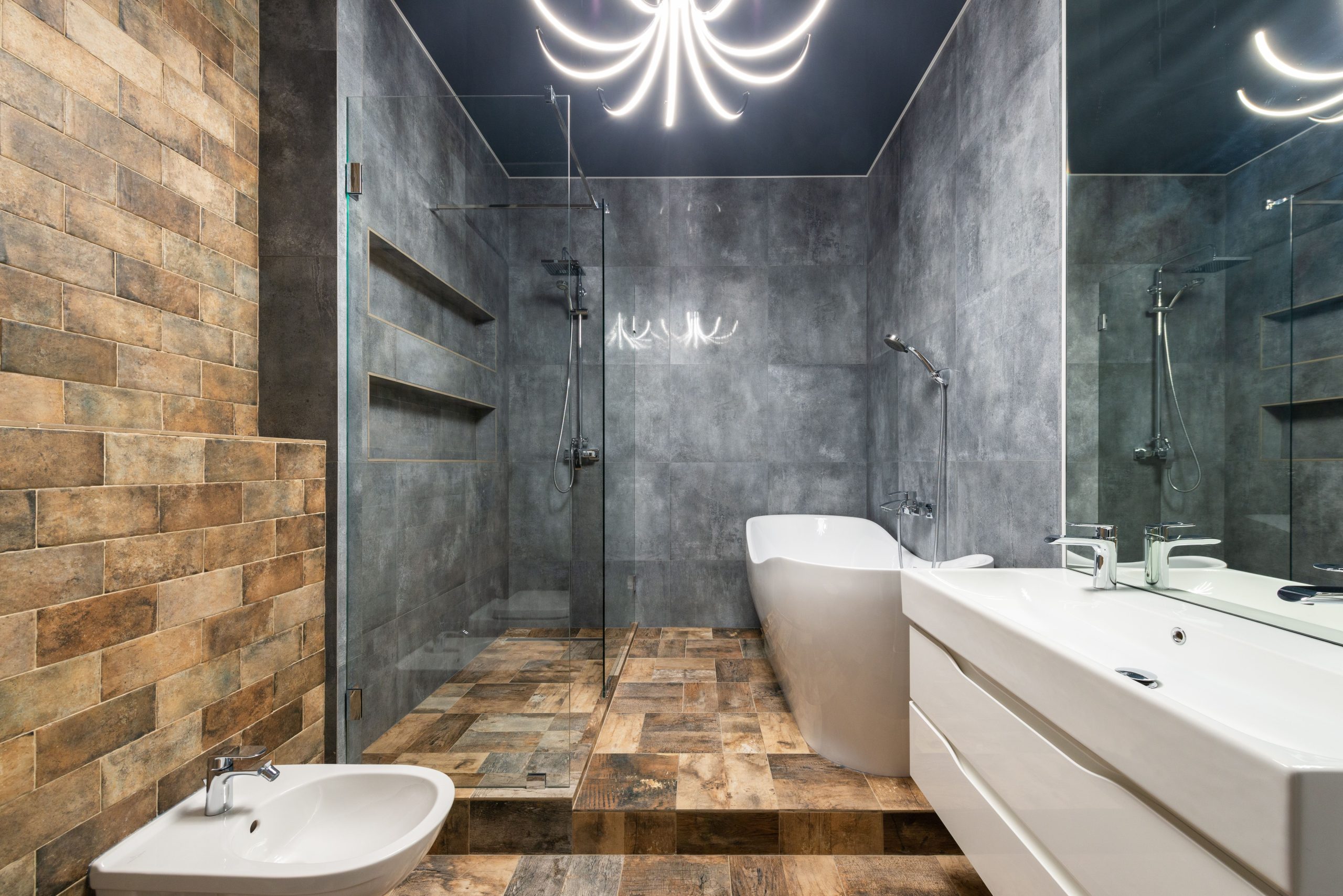 Interior of modern bathroom with sink with faucet under mirror in front of bidet next to bathtub and shower