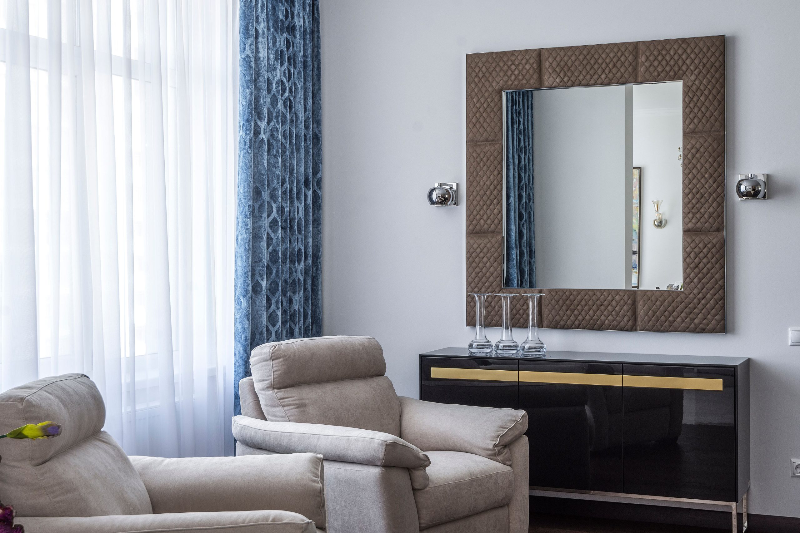 Interior of modern living room with comfy soft armchairs and square mirror in stylish apartment