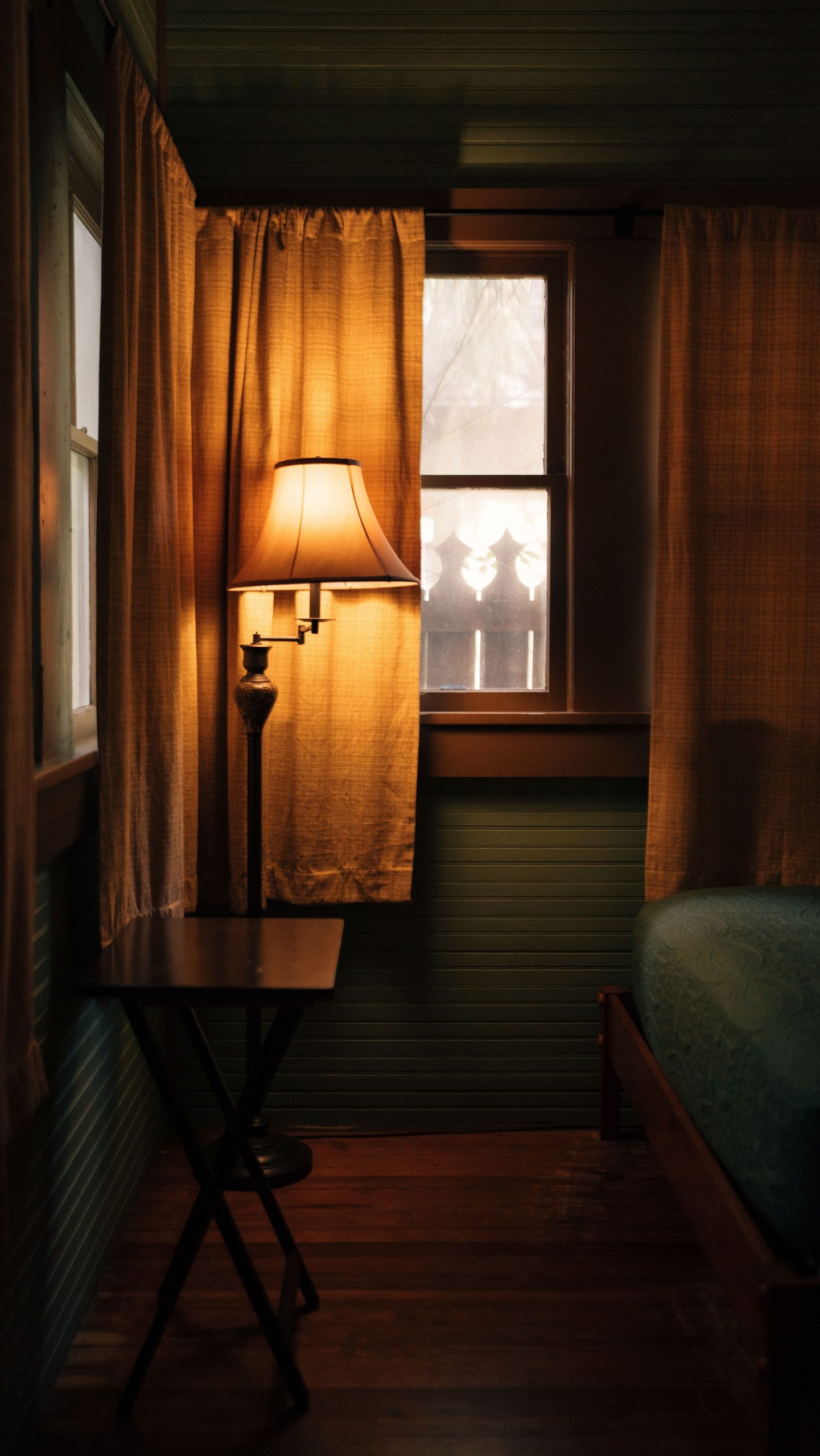 Inviting bedroom with glowing lamp, curtains, and wooden decor, perfect for relaxation.