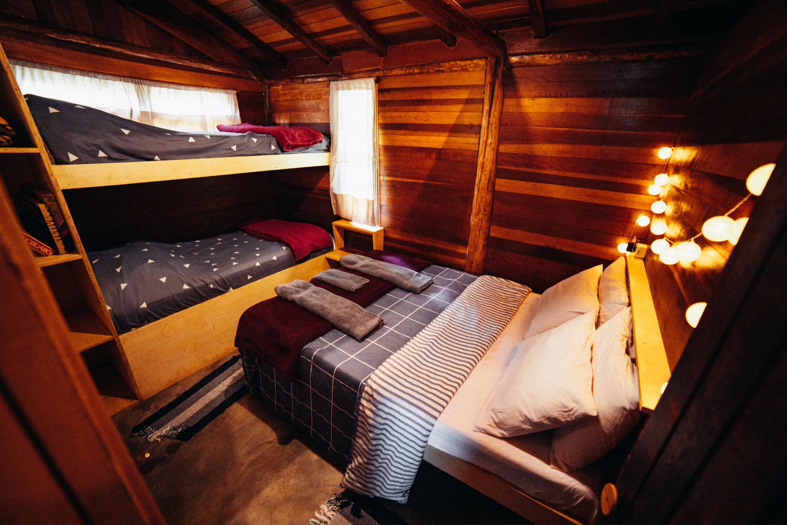 Inviting wooden cabin bedroom with cozy beds and warm lighting, perfect for a retreat.