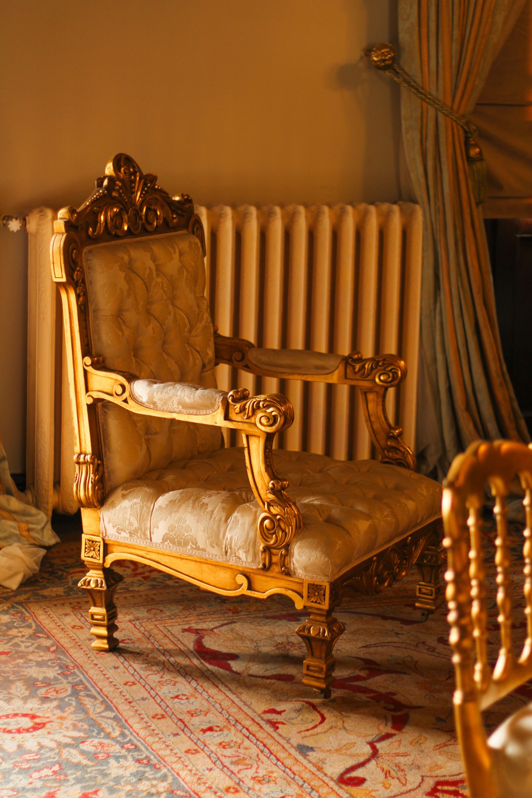 Luxurious antique wooden chair with ornate carvings in a warm, classic room setting.