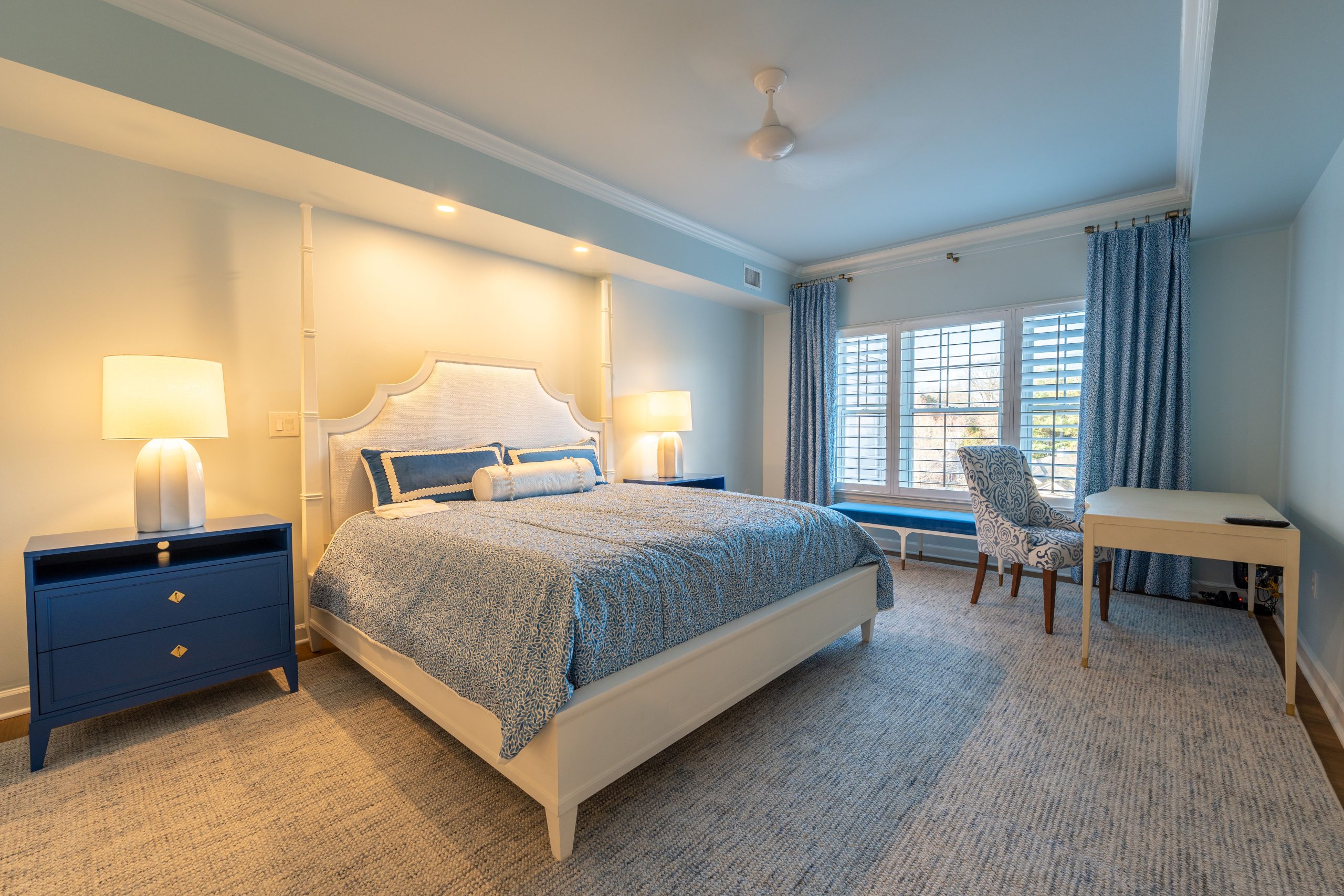Luxurious bedroom with blue and white decor, featuring a king-size bed, elegant furniture, and soft lighting.