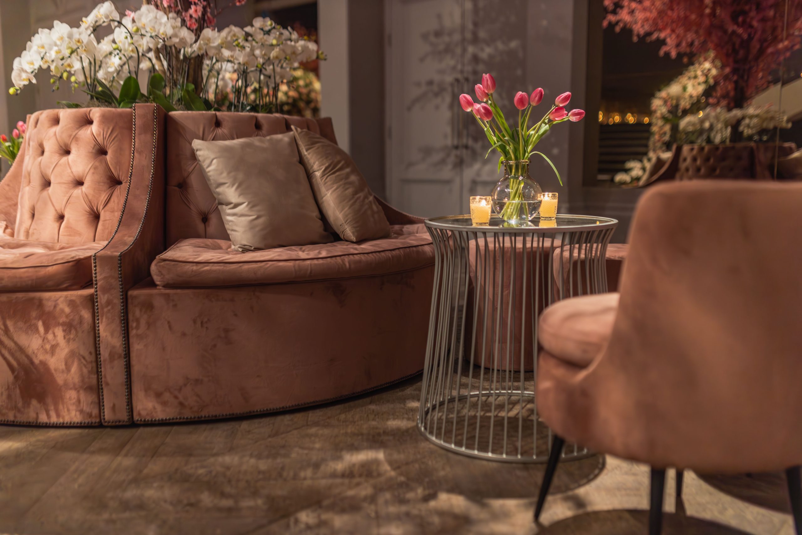 Luxurious indoor lounge featuring pink tulips and velvet seating, creating a warm ambiance.