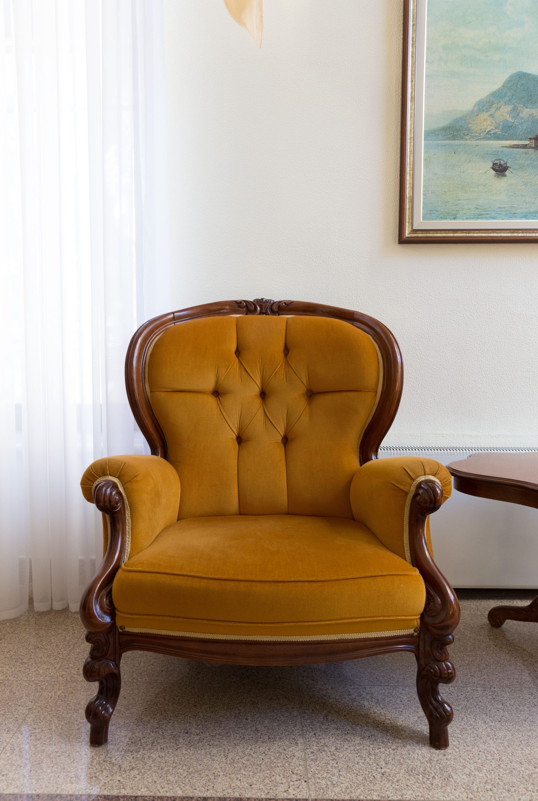 Luxurious vintage armchair with brown wooden frame in a bright, classic interior setting.