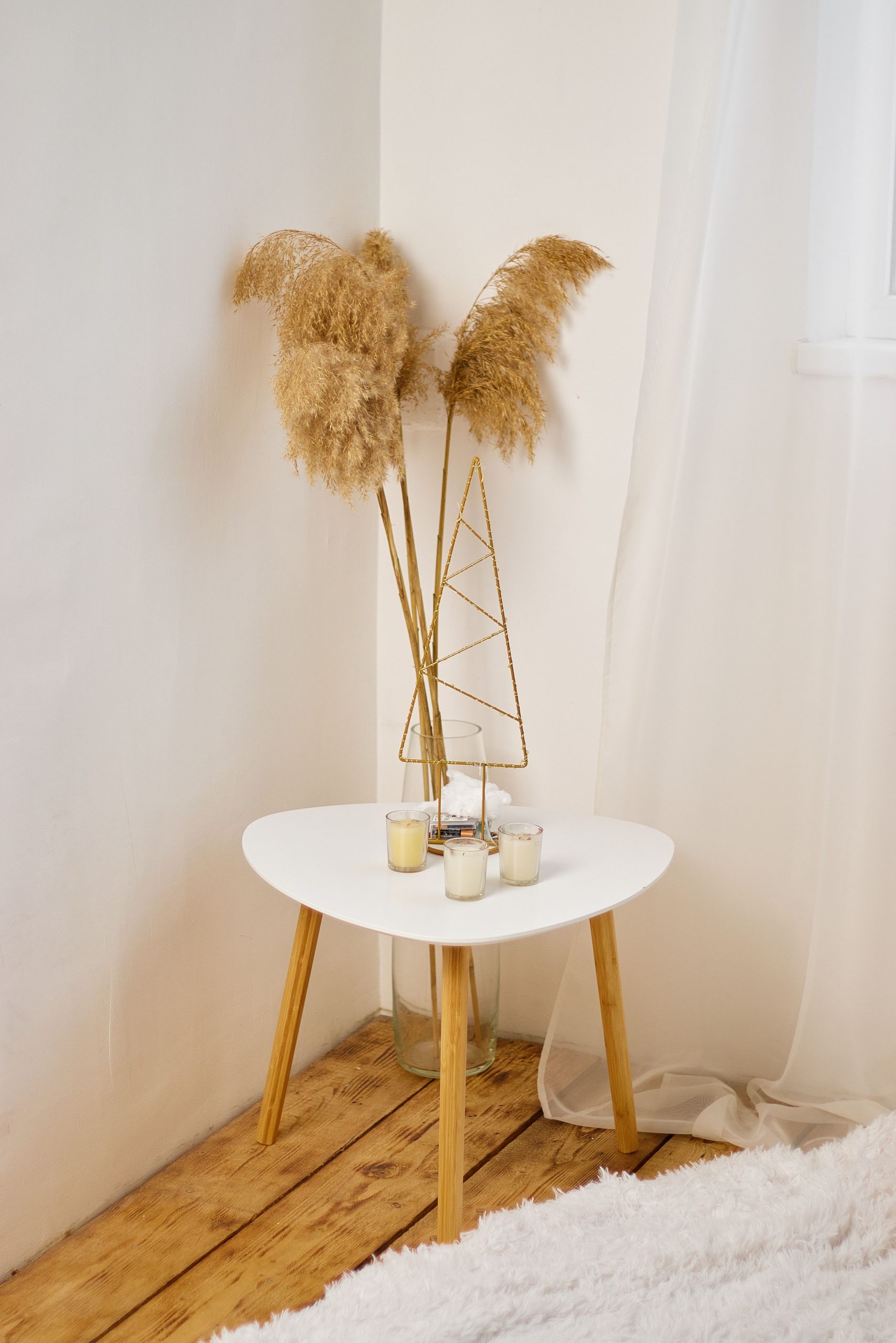 Minimalist interior design featuring dry grass in a vase on a coffee table with candles.