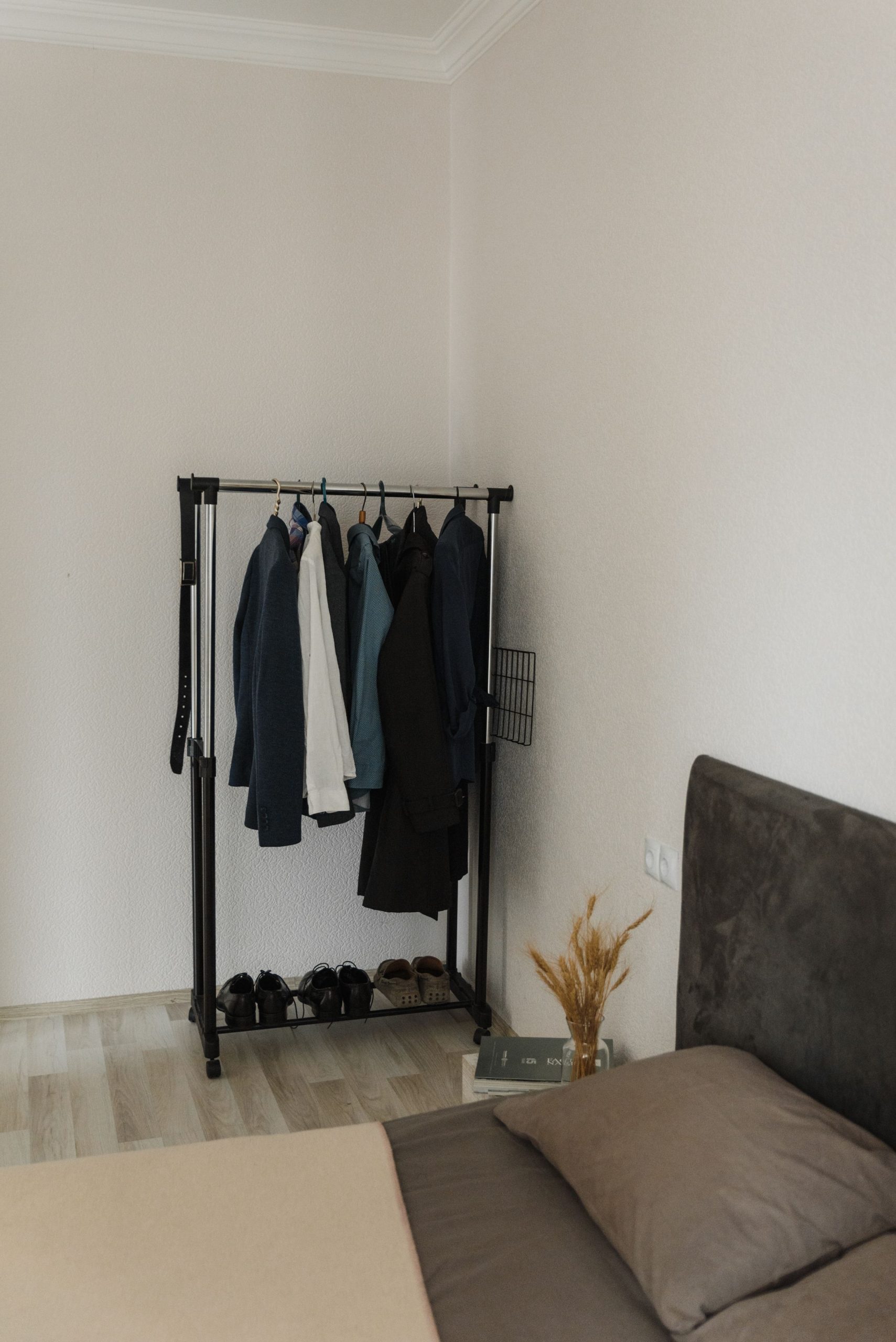 Modern bedroom featuring a clothes rack with hanging suits and shoes. Ideal for lifestyle or interior design themes.