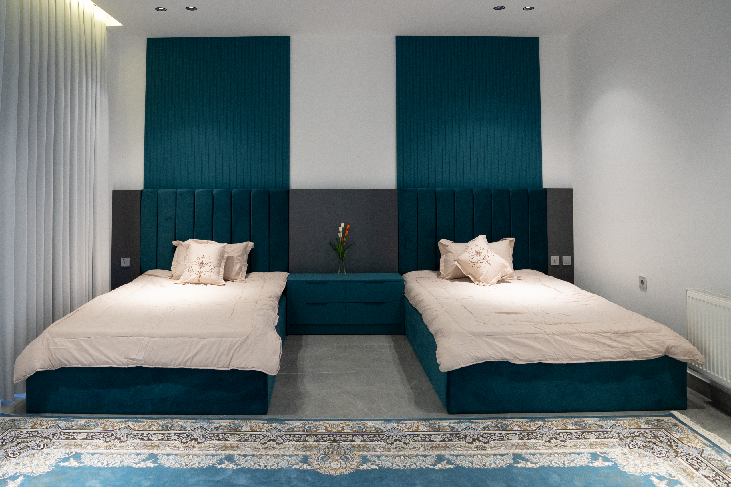 Modern twin bedroom with teal accents, stylish headboards, and cozy decor.