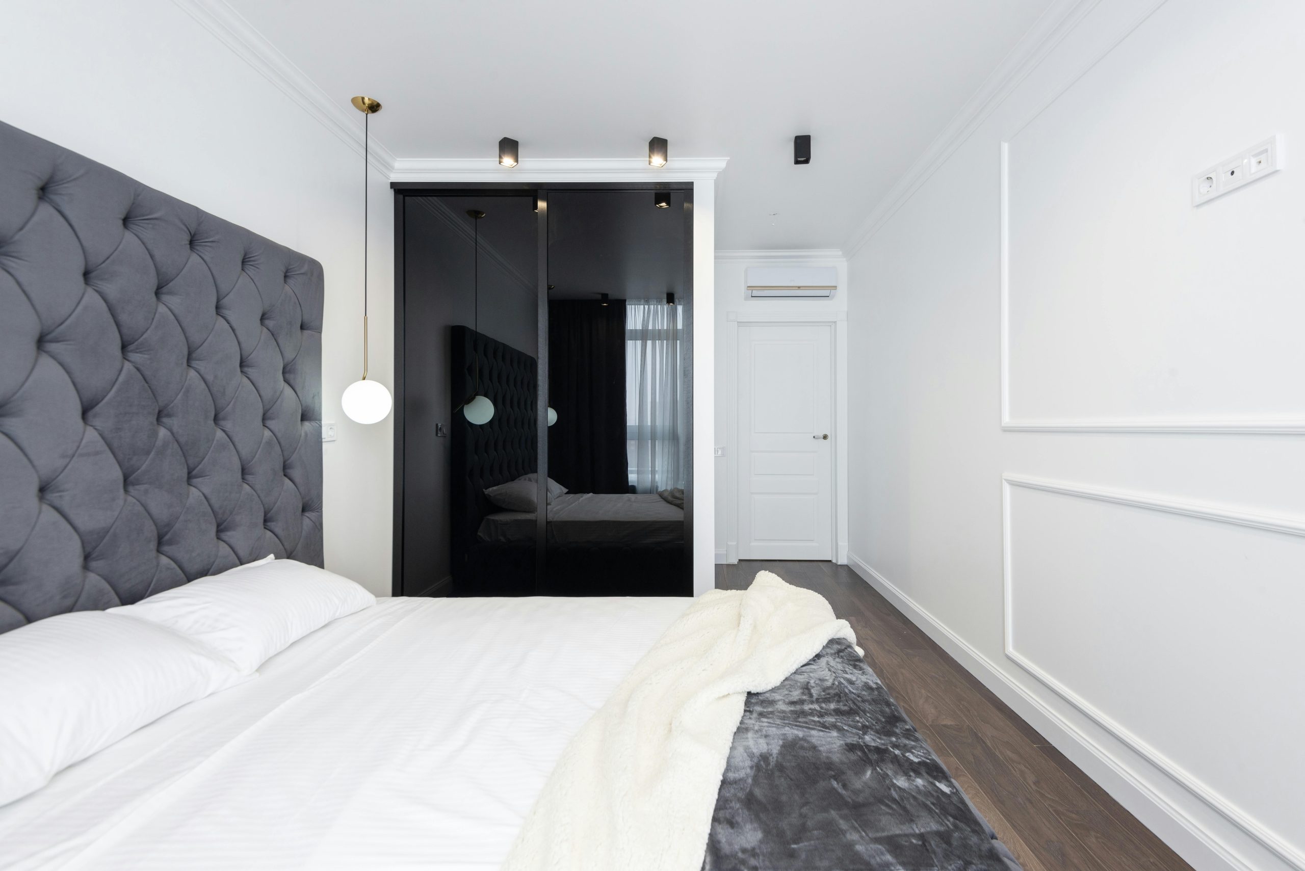 Sleek and contemporary bedroom with a grey headboard and white walls.